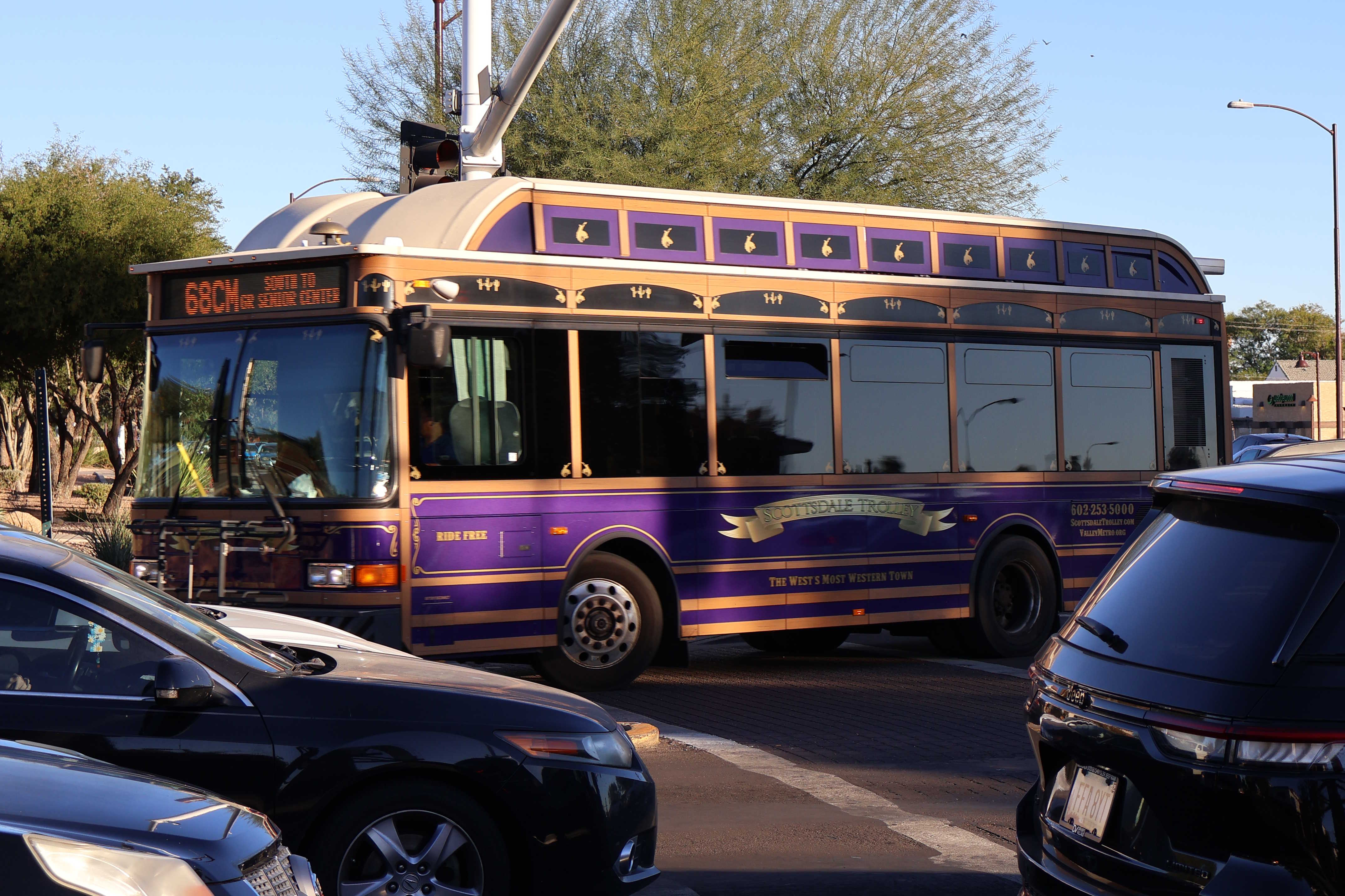 A purple, brown, and silver Scottsdale Trolley bus, number 4518, traveling northbound on Miller Road on the 68th Street/Camelback Trolley route to Granite Reef Senior Center