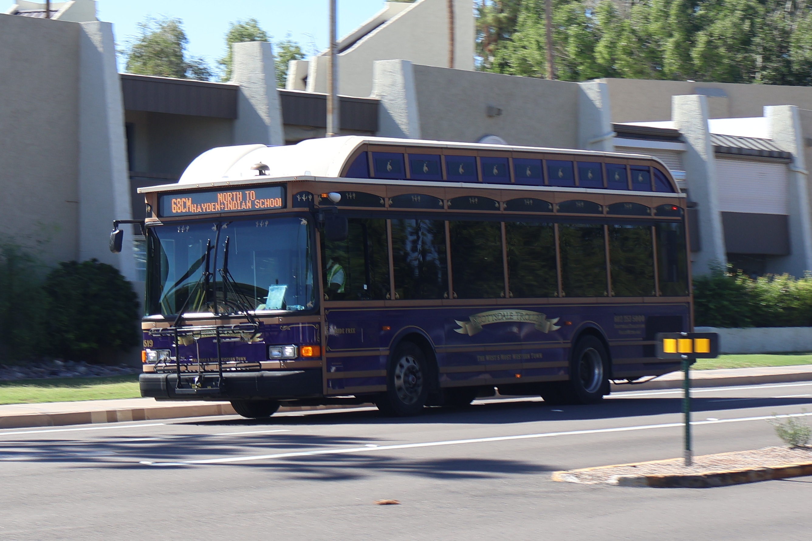 A purple, brown, and silver Scottsdale Trolley bus, number 4519, traveling eastbound on Camelback Road on the 68th Street/Camelback Trolley route to Indian School Road and Hayden Road