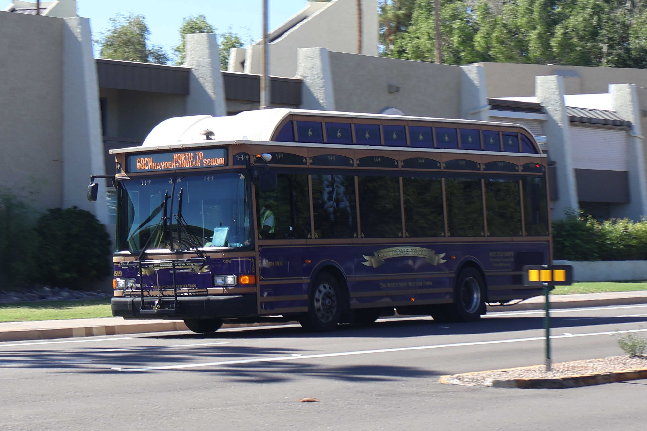 A purple, brown, and silver Scottsdale Trolley bus, number 4519, traveling eastbound on Camelback Road on the 68th Street/Camelback Trolley route to Indian School Road and Hayden Road