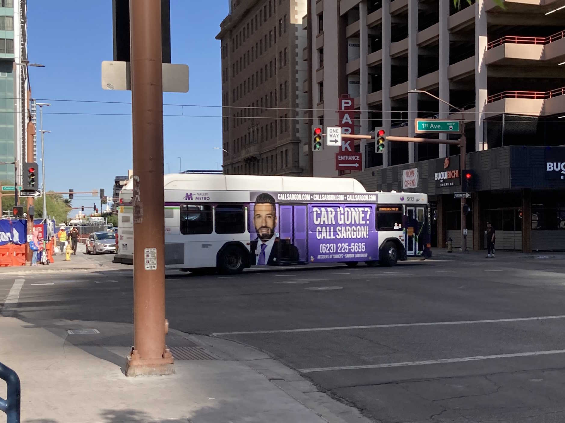 A white and gray Valley Metro bus, with purple and green accent colors, number 5247, turning onto Van Buren Street, westbound, in Phoenix on route 7 to Baseline and 7th Street