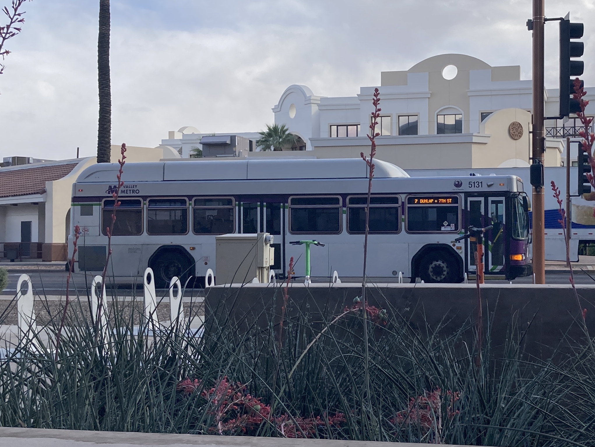 A white and gray Valley Metro bus, with purple and green accent colors, number 5131, traveling eastbound on Van Buren Street in Phoenix on route 7 to 7th Street and Dunlap Avenue