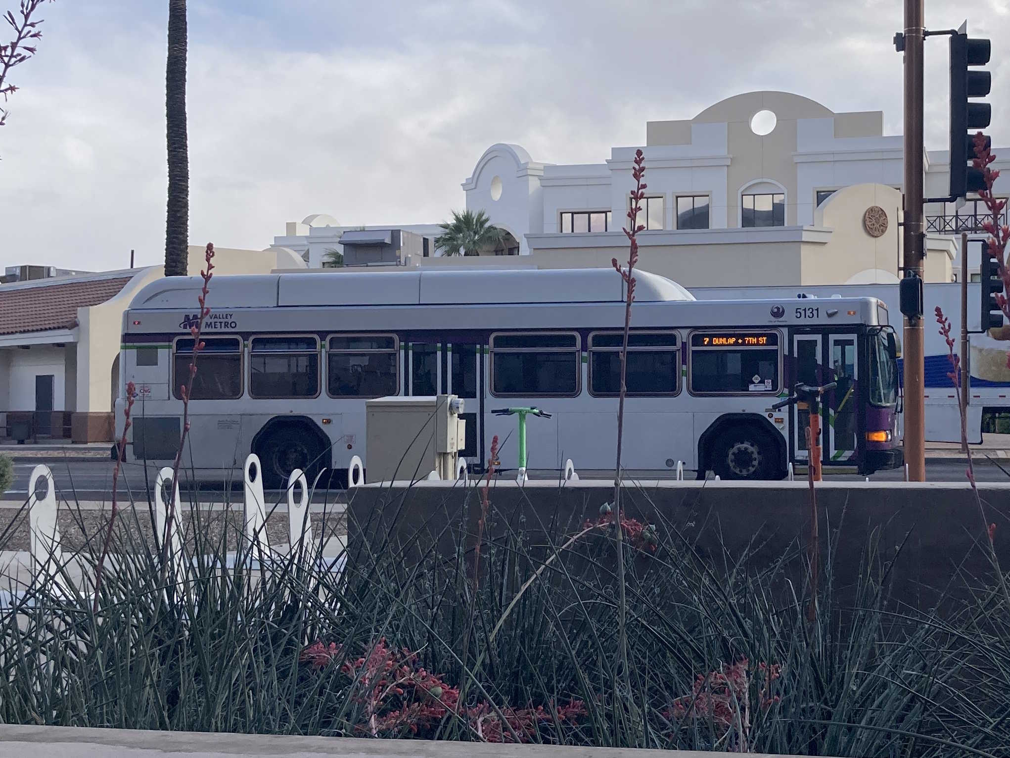 A white and gray Valley Metro bus, with purple and green accent colors, number 5131, traveling eastbound on Van Buren Street in Phoenix on route 7 to 7th Street and Dunlap Avenue