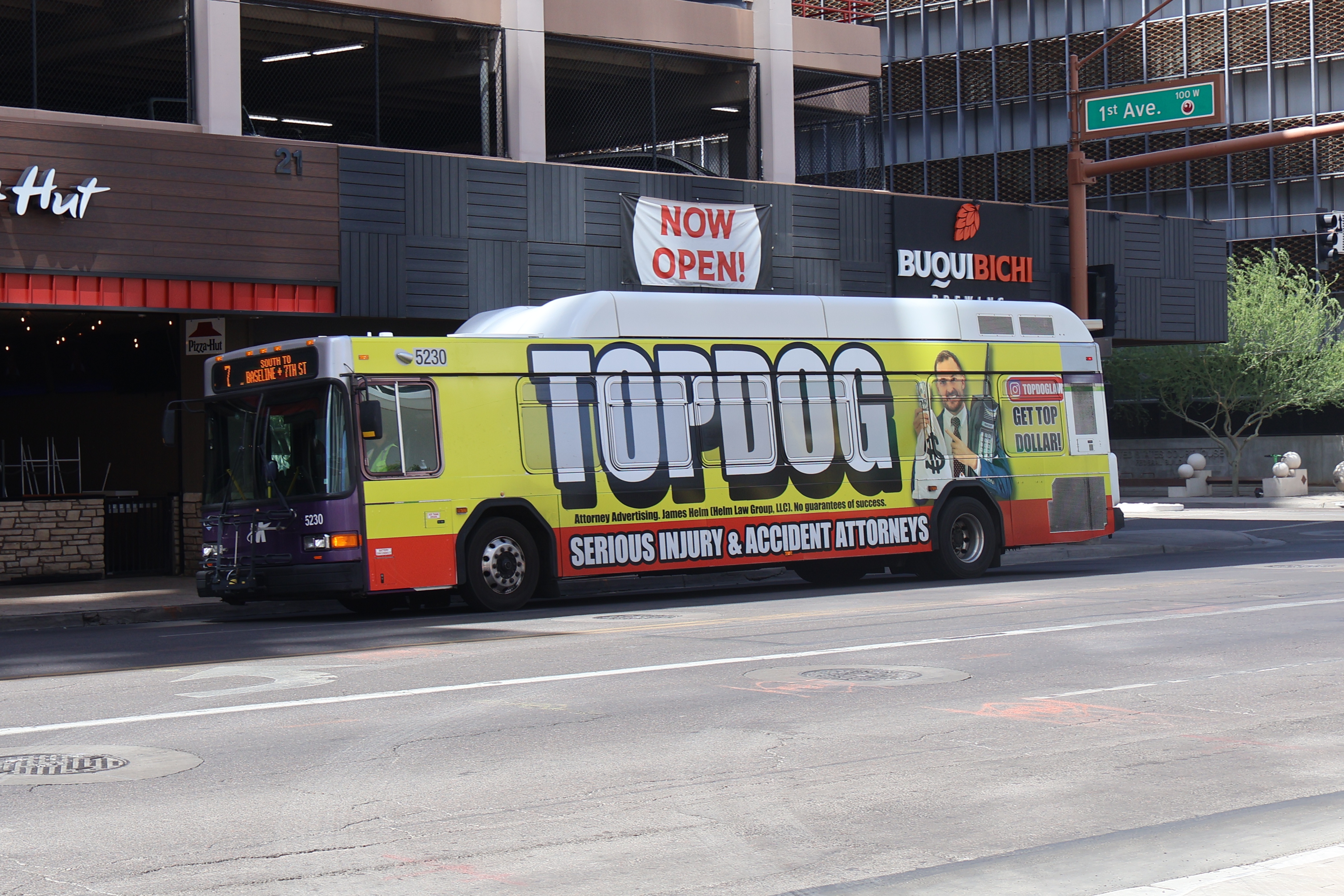 A white and gray Valley Metro bus, with purple and green accent colors, number 5230, traveling eastbound on Van Buren Street in Phoenix on route 7 to 7th Street and Baseline Road