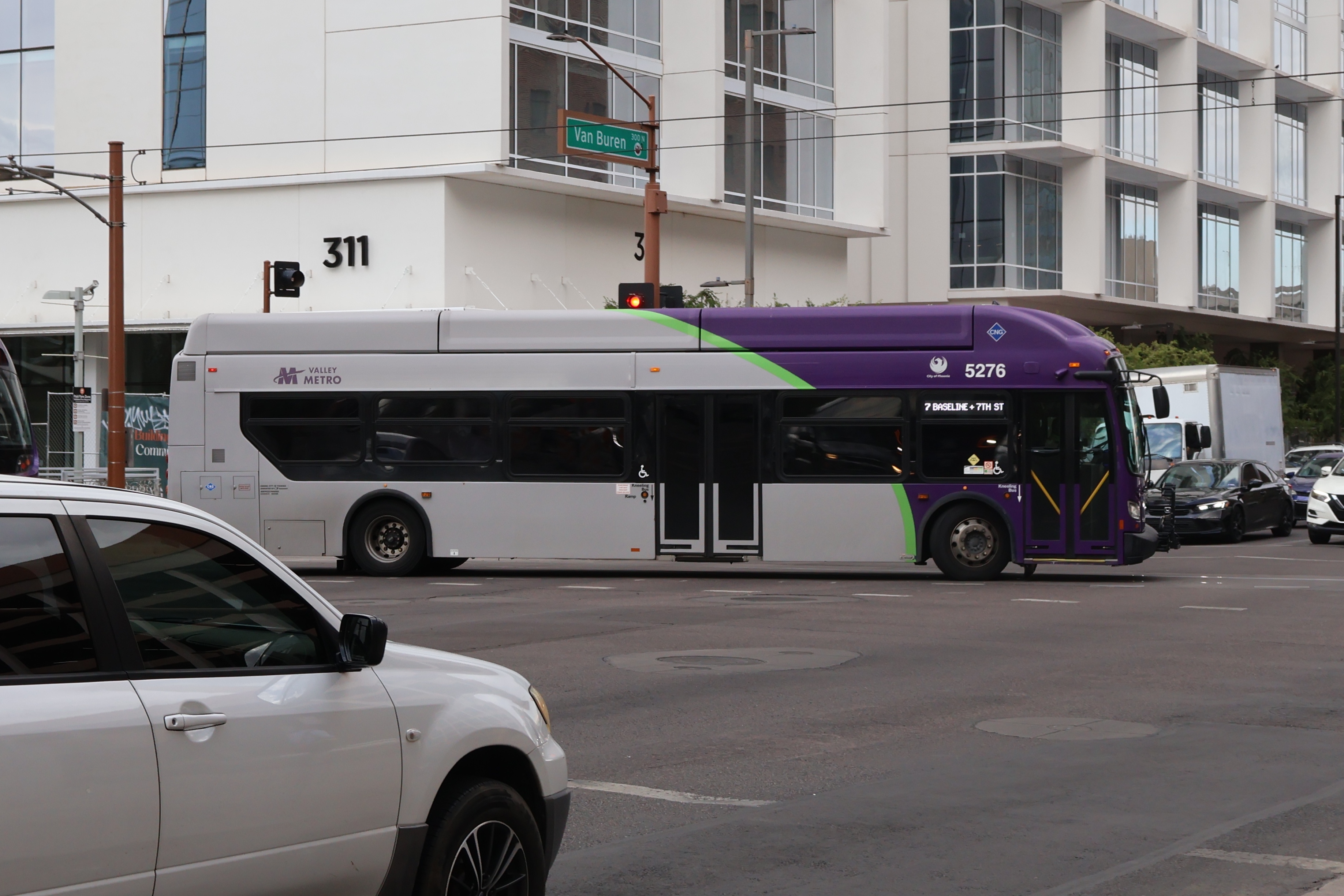 A gray and purple Valley Metro bus, with a green stripe, number 5276, traveling southbound on 1st Avenue in Phoenix on route 7 to 7th Street and Baseline Road