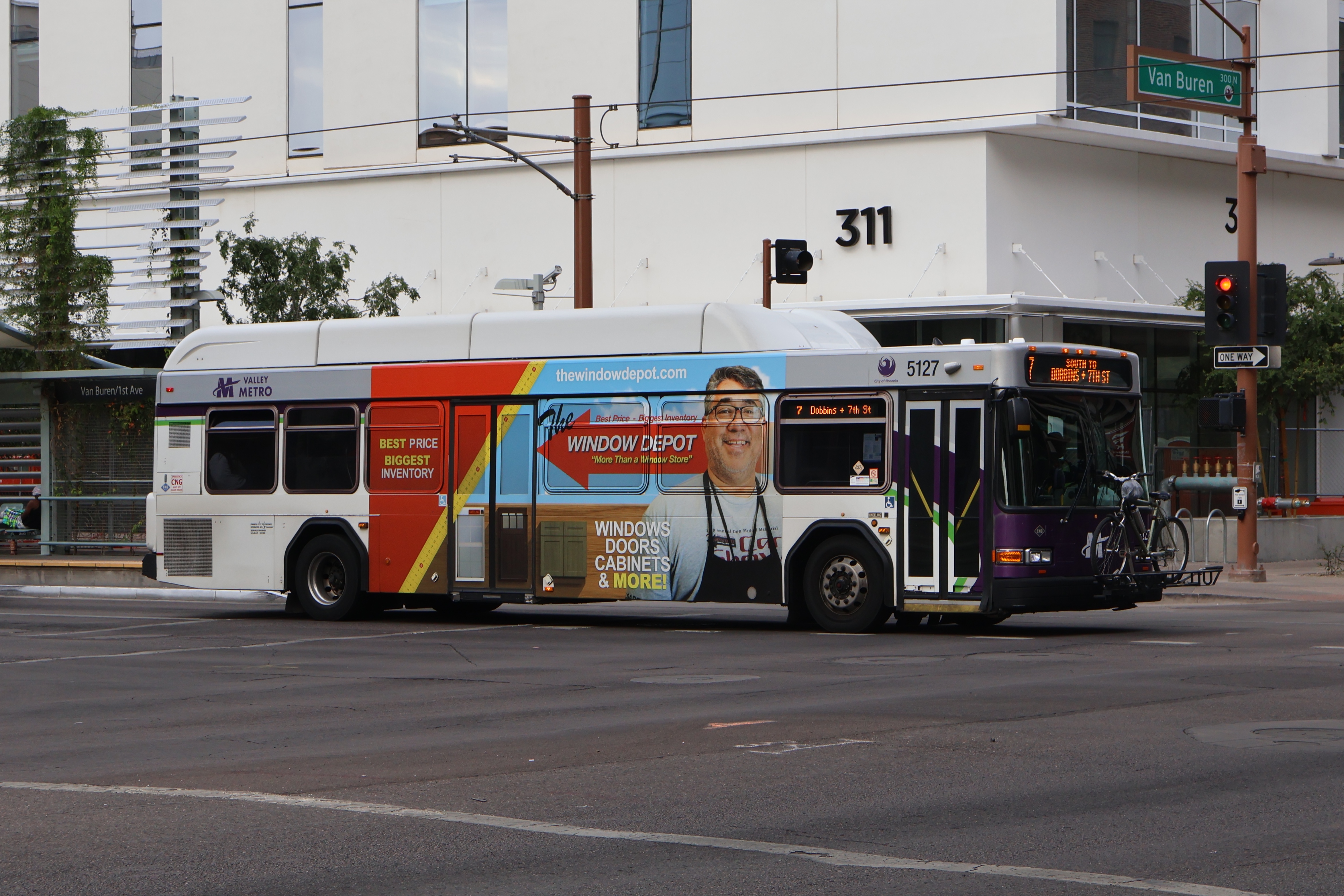 A white and gray Valley Metro bus, with purple and green accent colors, number 5127, traveling southbound on 1st Avenue in Phoenix on route 7 to 7th Street and Dobbins Road