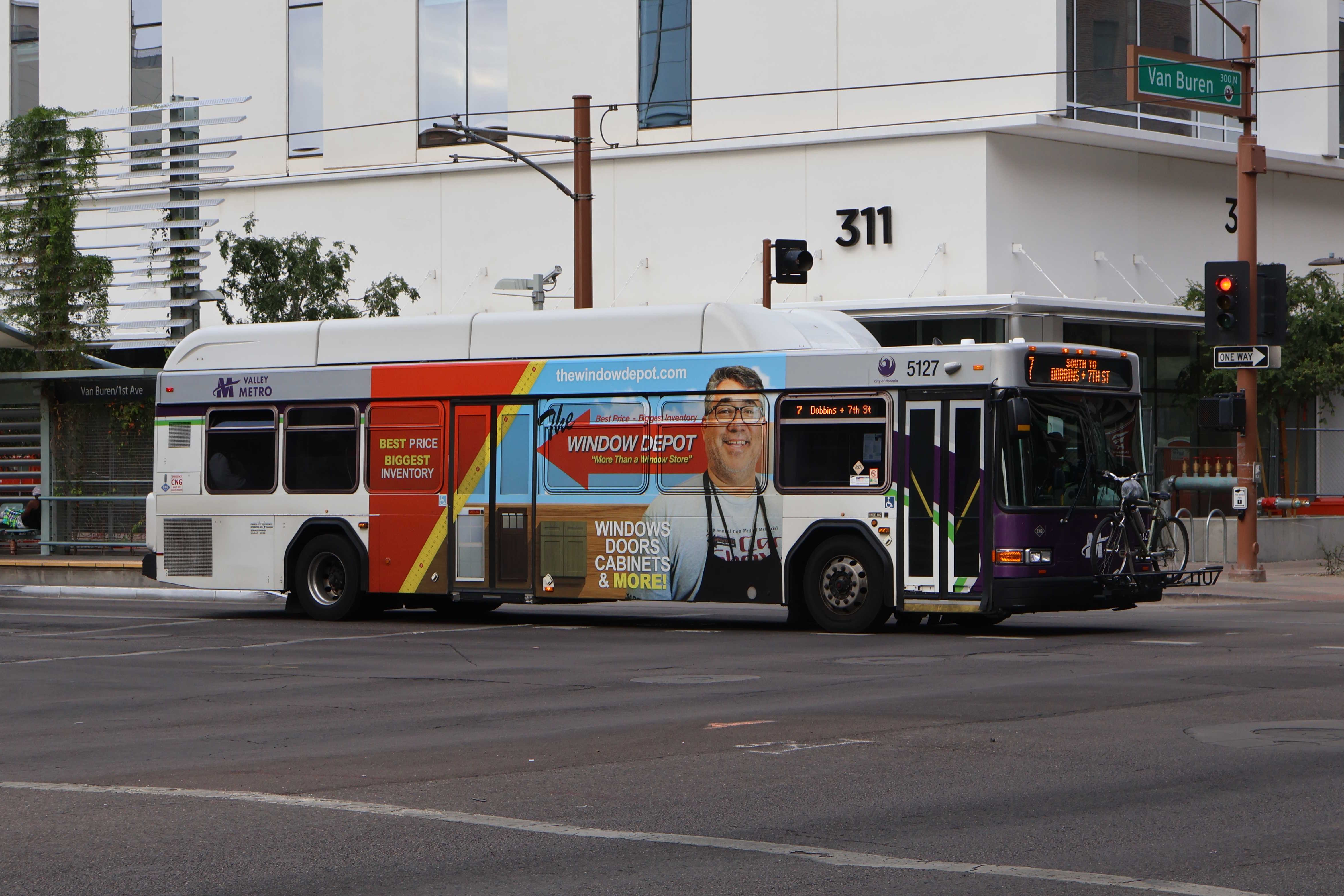 A white and gray Valley Metro bus, with purple and green accent colors, number 5127, traveling southbound on 1st Avenue in Phoenix on route 7 to 7th Street and Dobbins Road