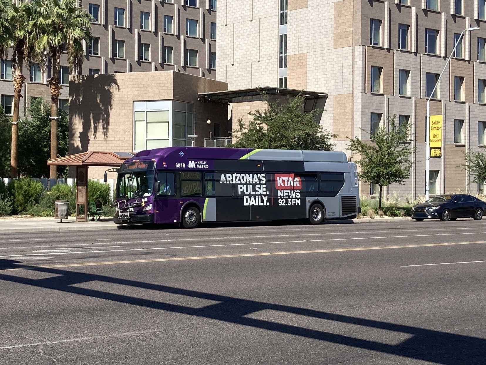 A gray and purple Valley Metro bus, with a green stripe, number 6818, traveling southbound on Rural Road in Tempe on route 72 to Chandler Fashion Center