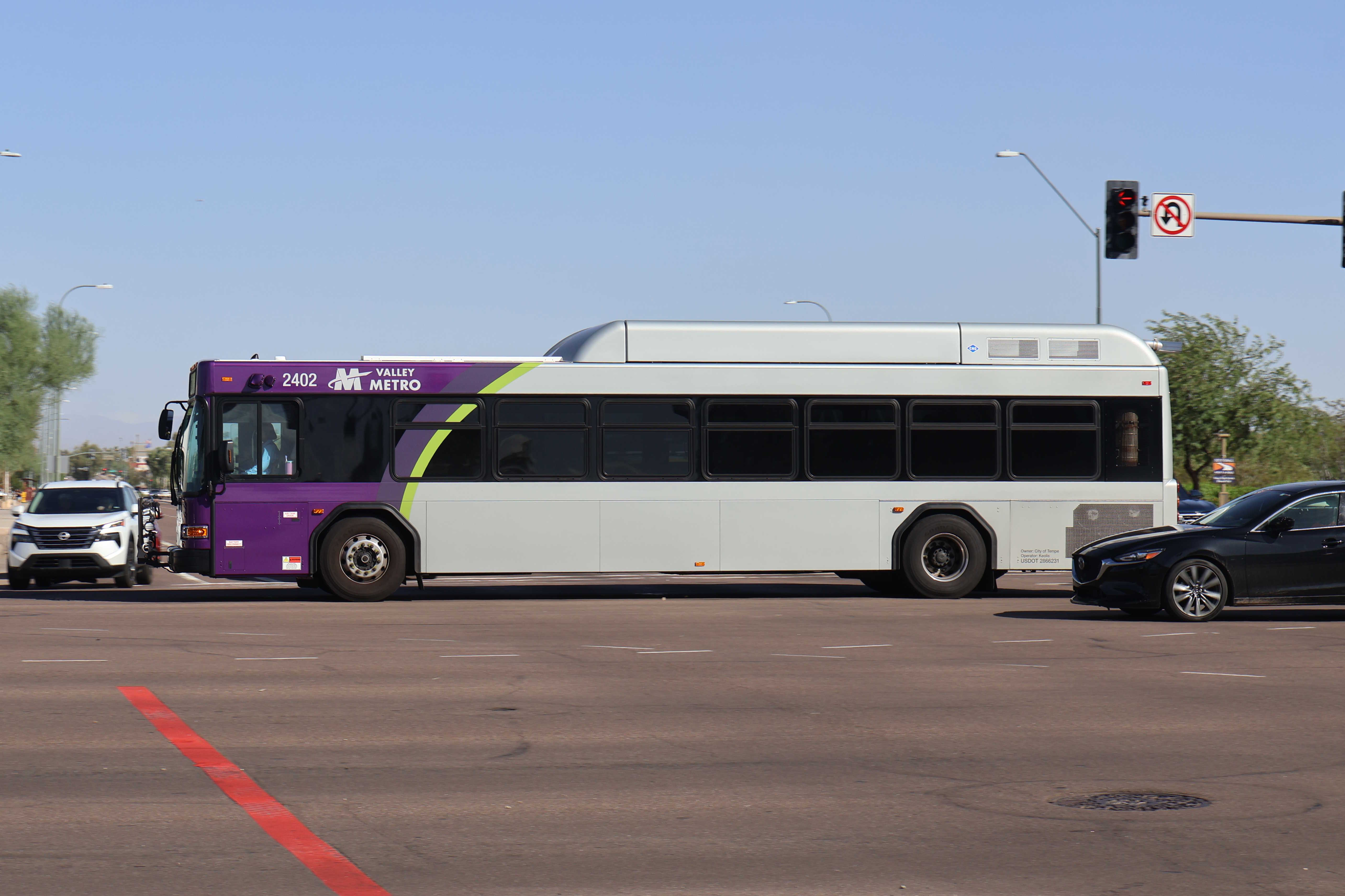 A gray and purple Valley Metro bus, with a green stripe, number 2402, traveling northbound on Scottsdale Road in Scottsdale on route 72 to Thompson Peak Parkway and Scottsdale Healthcare