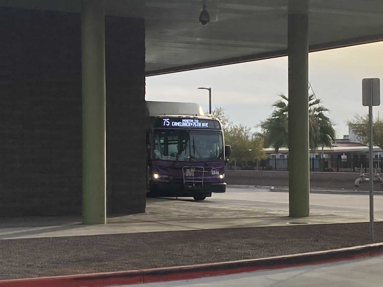 A white and gray Valley Metro bus, with purple and green accent colors, number 5048, at Desert Sky Transit Center in Phoenix on route 75 to 75th Avenue and Camelback Road