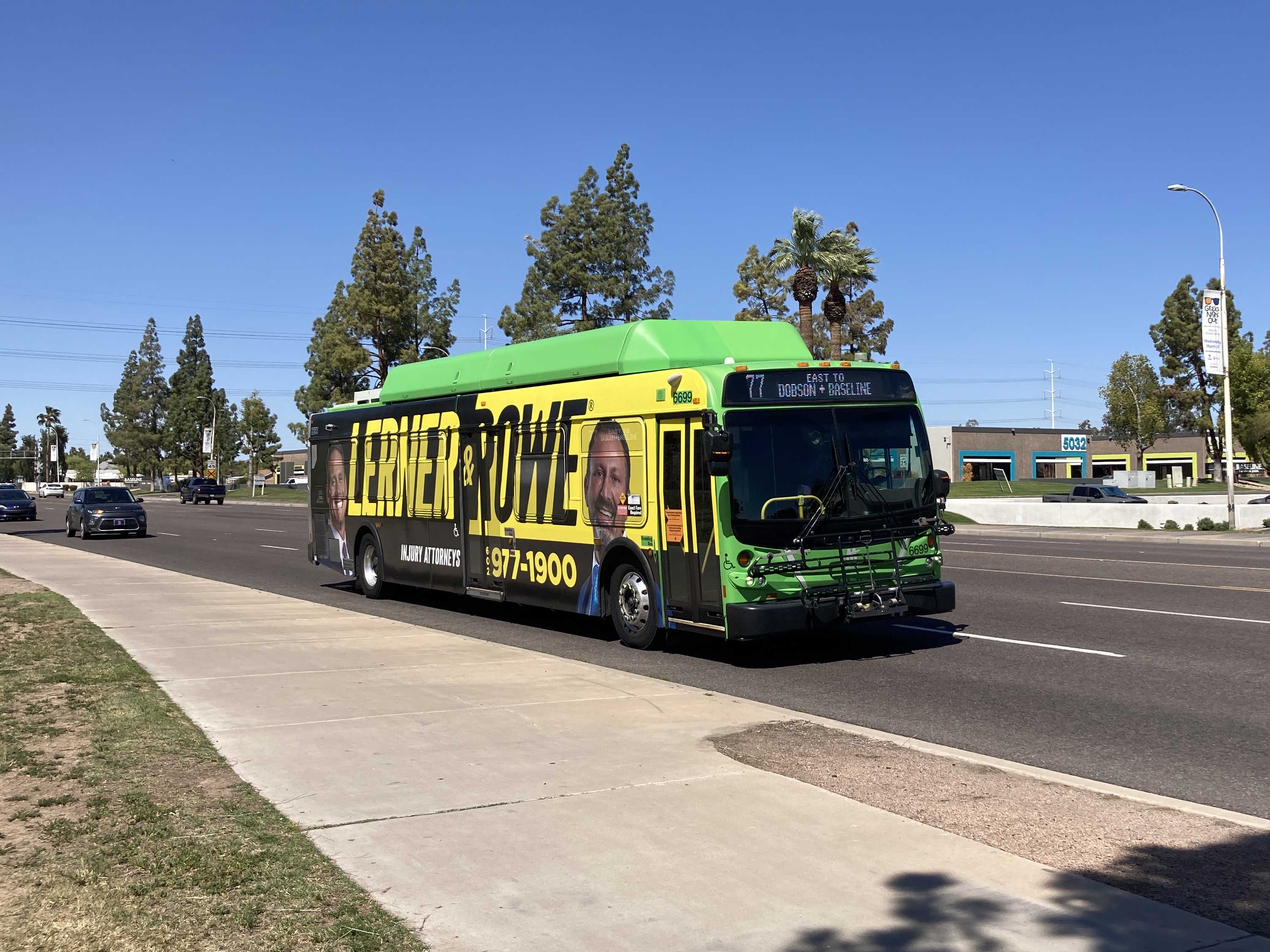 A green Valley Metro bus, number 6699, traveling eastbound on Baseline Road on route 77 to Baseline Road & Dobson Road