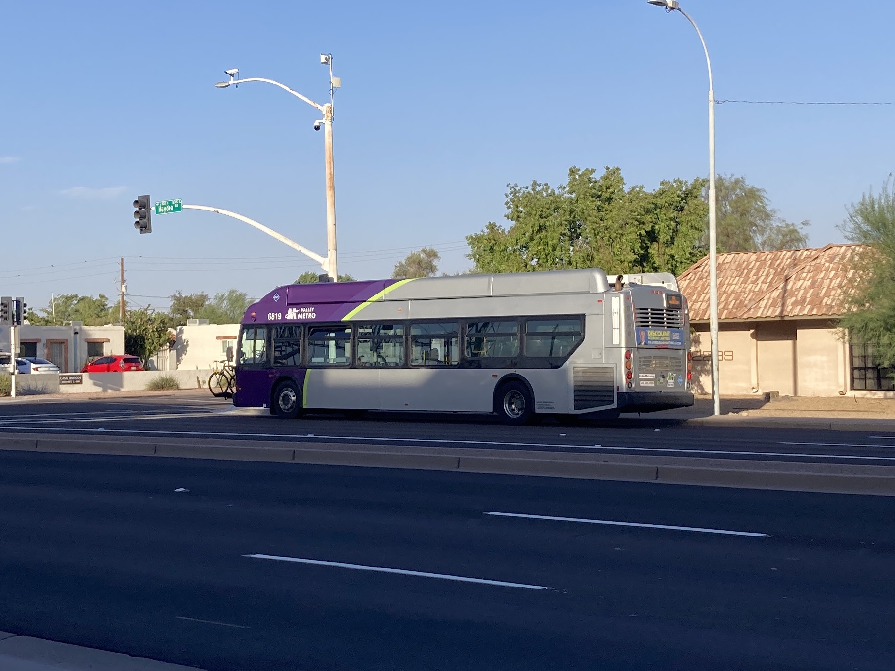 A gray and purple Valley Metro bus with a green stripe, number 6819, traveling northbound on Hayden Road in Scottsdale on route 81 to Mustang Transit Center