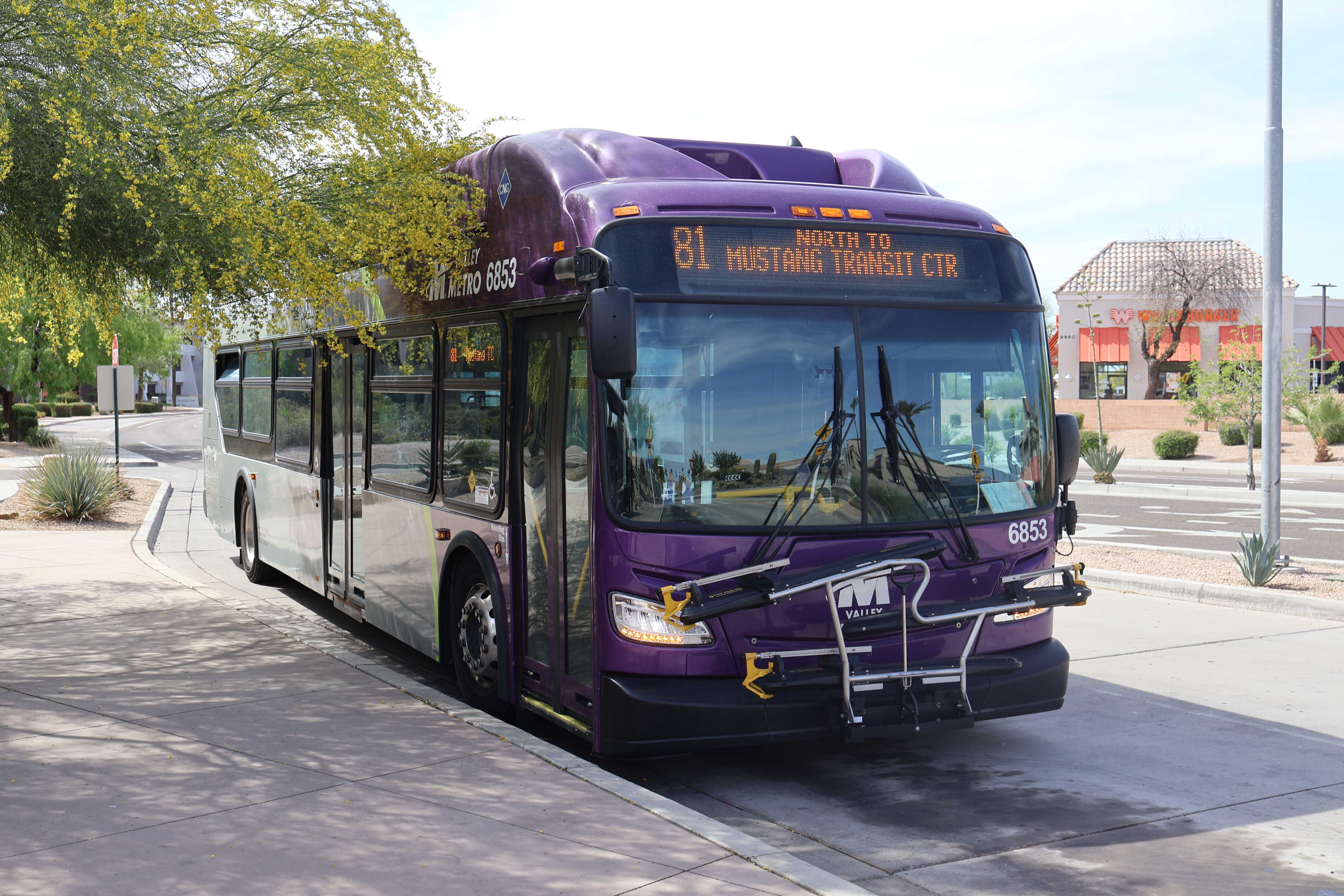 A gray and purple Valley Metro bus with a green stripe, number 6853, at Mustang Transit Center in Scottsdale on route 81 to Mustang Transit Center