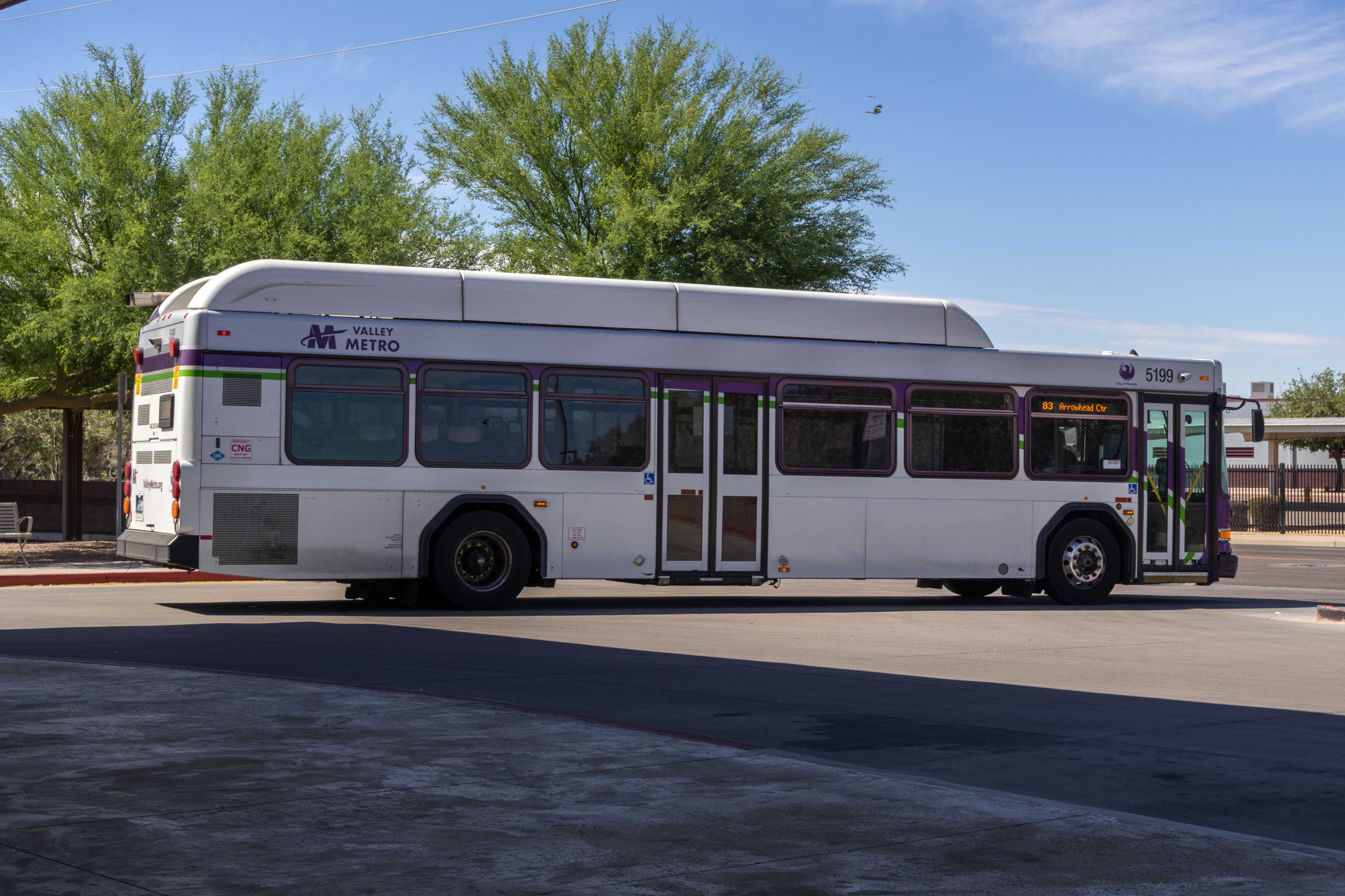 A white and gray Valley Metro bus, with purple and green accent colors, number 5199, at Desert Sky Transit Center in Phoenix on route 83 to Arrowhead Mall Transit Center