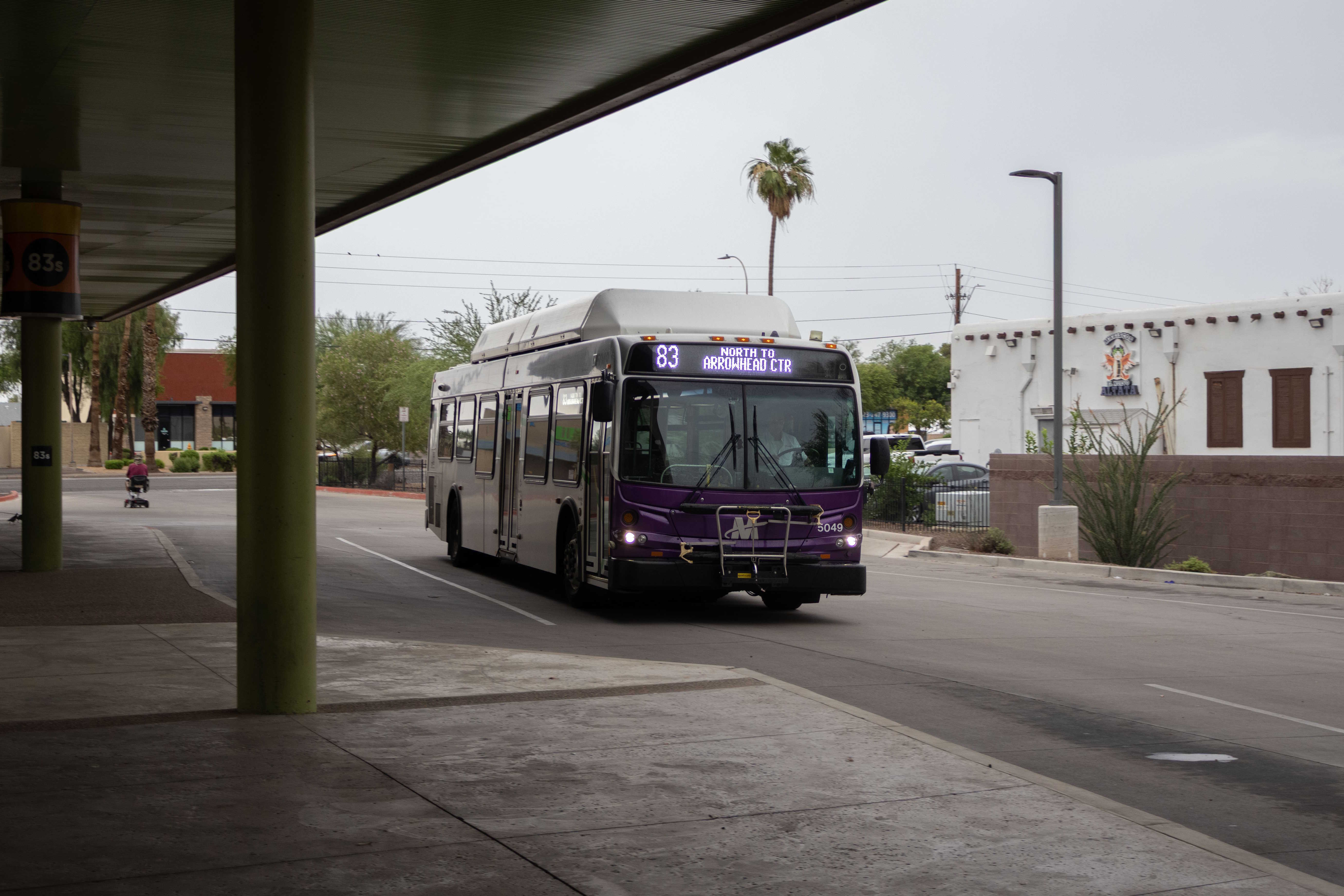 A white and gray Valley Metro bus, with purple and green accent colors, number 5049, at Desert Sky Transit Center in Phoenix on route 83 to Arrowhead Mall Transit Center