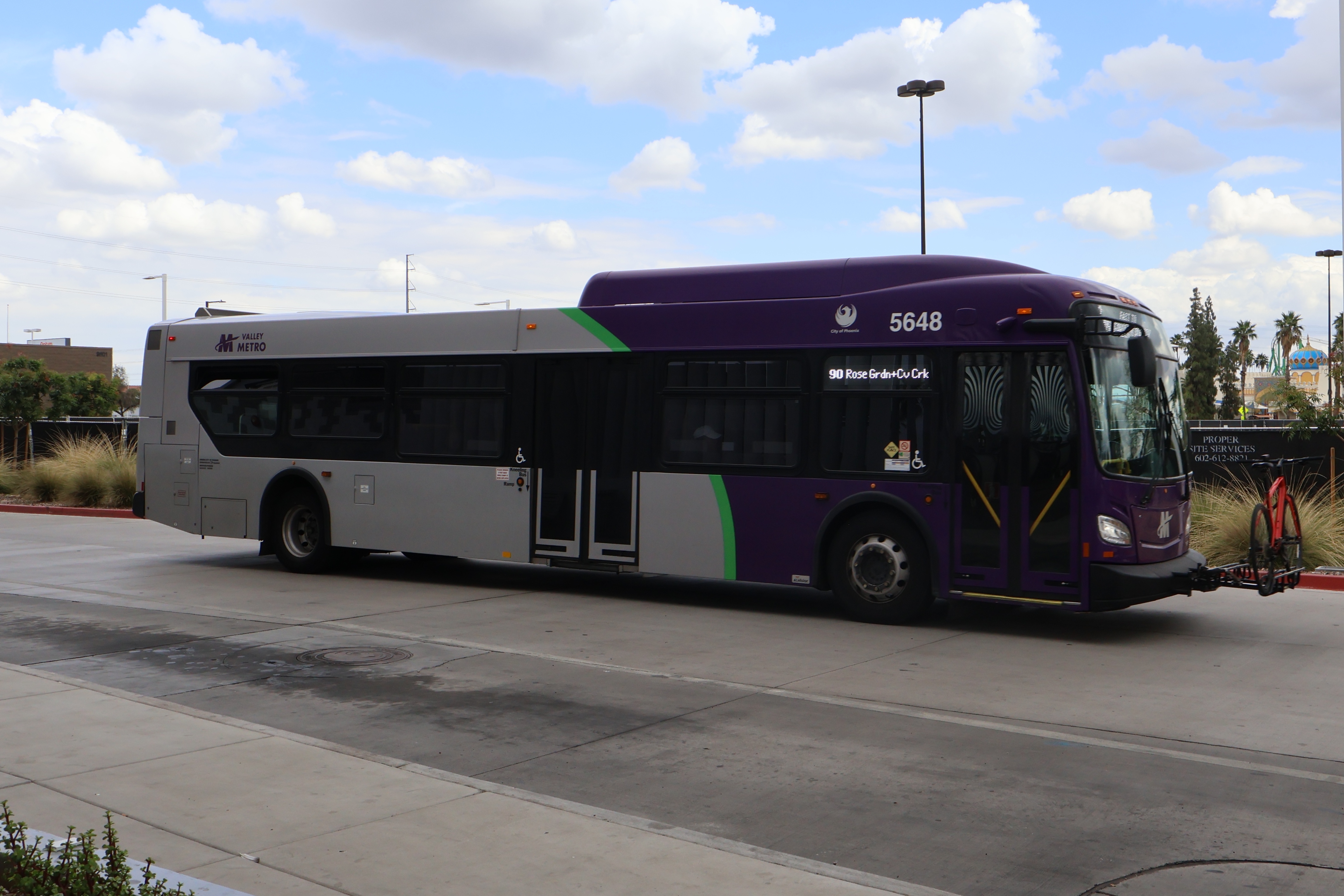 A gray and purple Valley Metro bus, with a green stripe, number 5648, at Thelda Williams Transit Center in Phoenix on route 90 to Cave Creek Road and Rose Garden Lane
