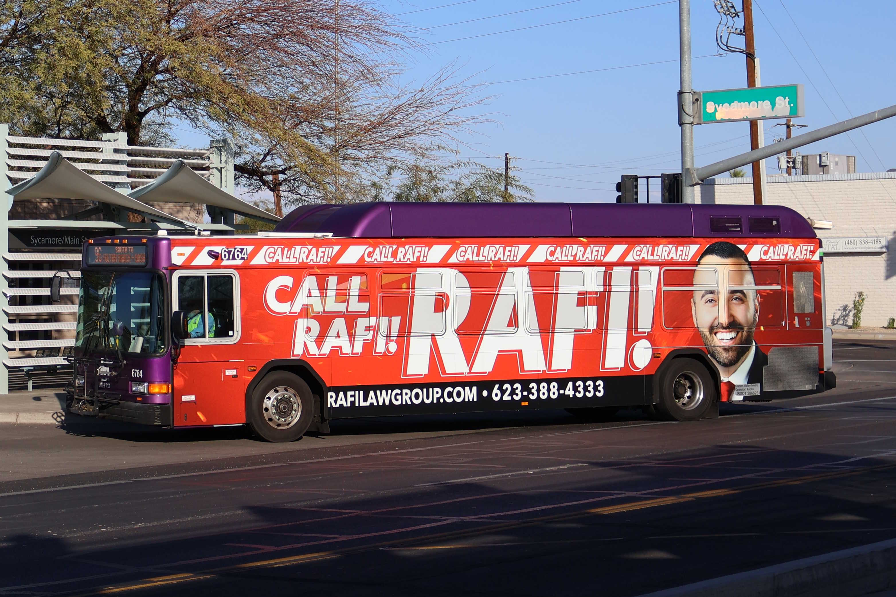 A gray and purple Valley Metro bus with a white and green stripe, number 6764, traveling westbound on Main Street in Mesa on route 96 to Basha Road and Fulton Ranch Boulevard