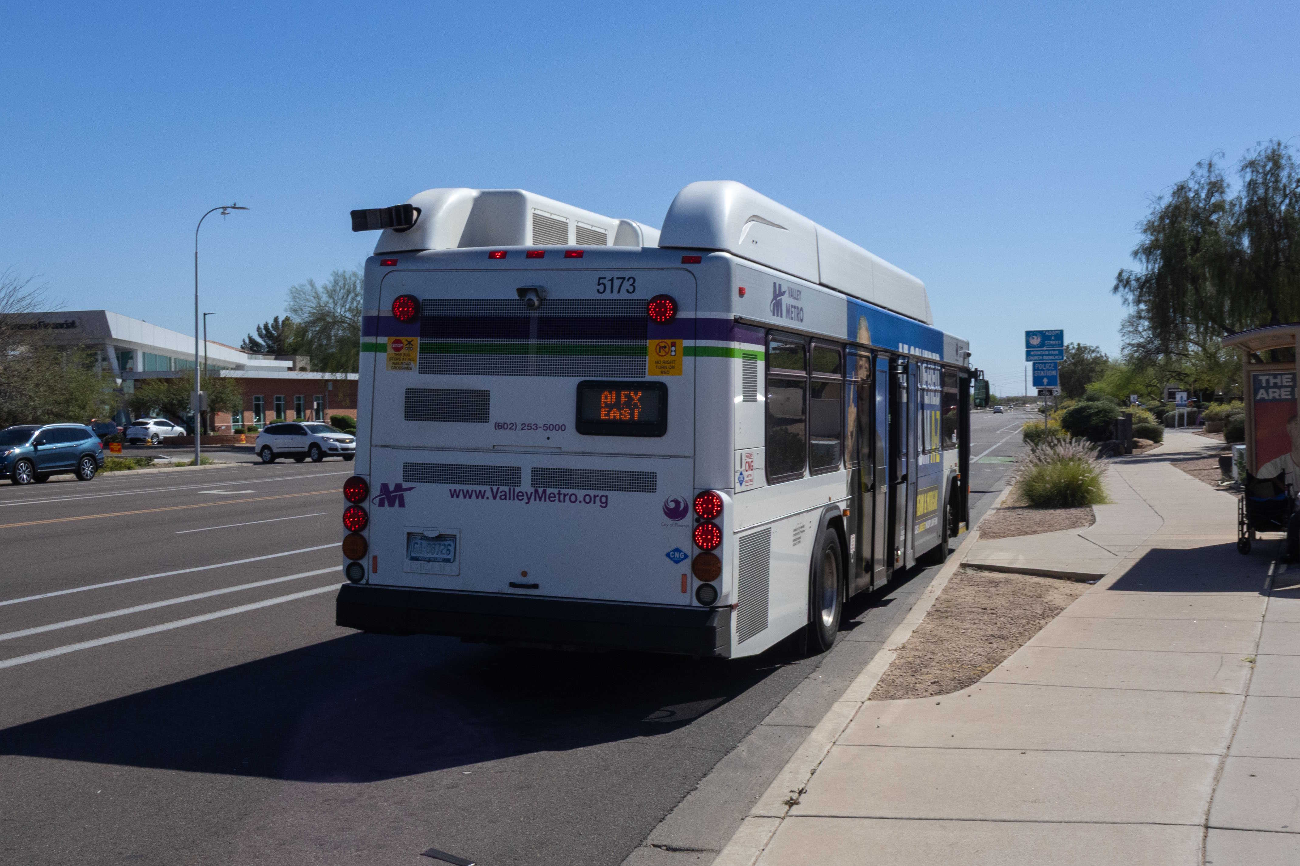 A white and gray Valley Metro bus, with purple and green accent colors, number 5173, traveling southbound on 48th Street in Phoenix on the ALEX route to 51st Street and Elliot Road