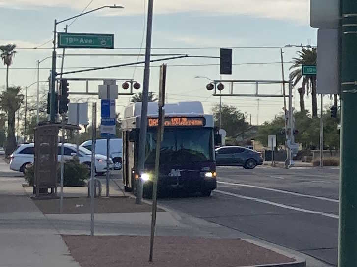 A white and gray Valley Metro bus, with purple and green accent colors, number 5129, traveling eastbound on Jefferson Street in Phoenix on the DASH route to Washington Street and 4th Street