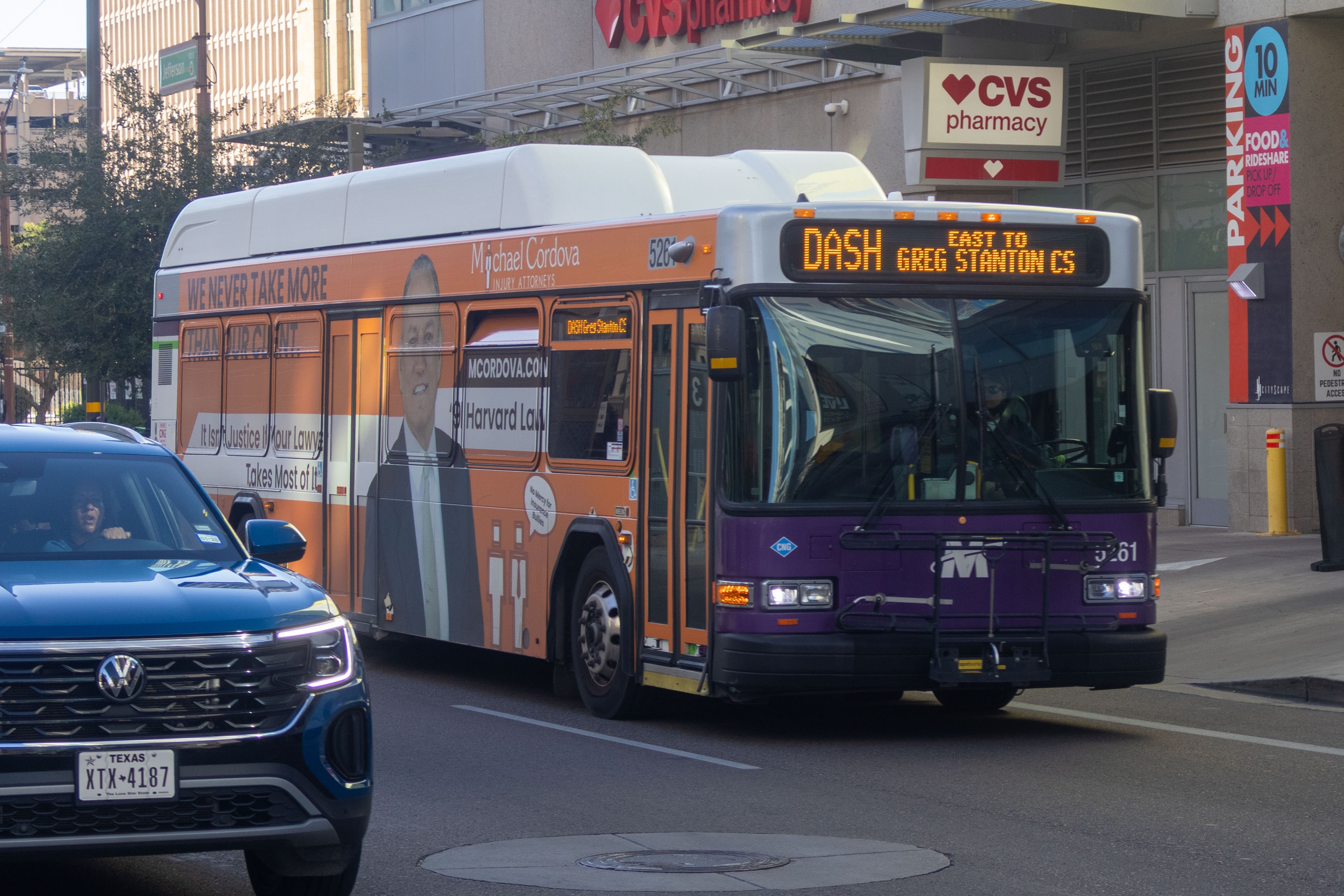 A white and gray Valley Metro bus, with purple and green accent colors, number 5261, traveling eastbound on Jefferson Street in Phoenix on the DASH route to Greg Stanton Central Station