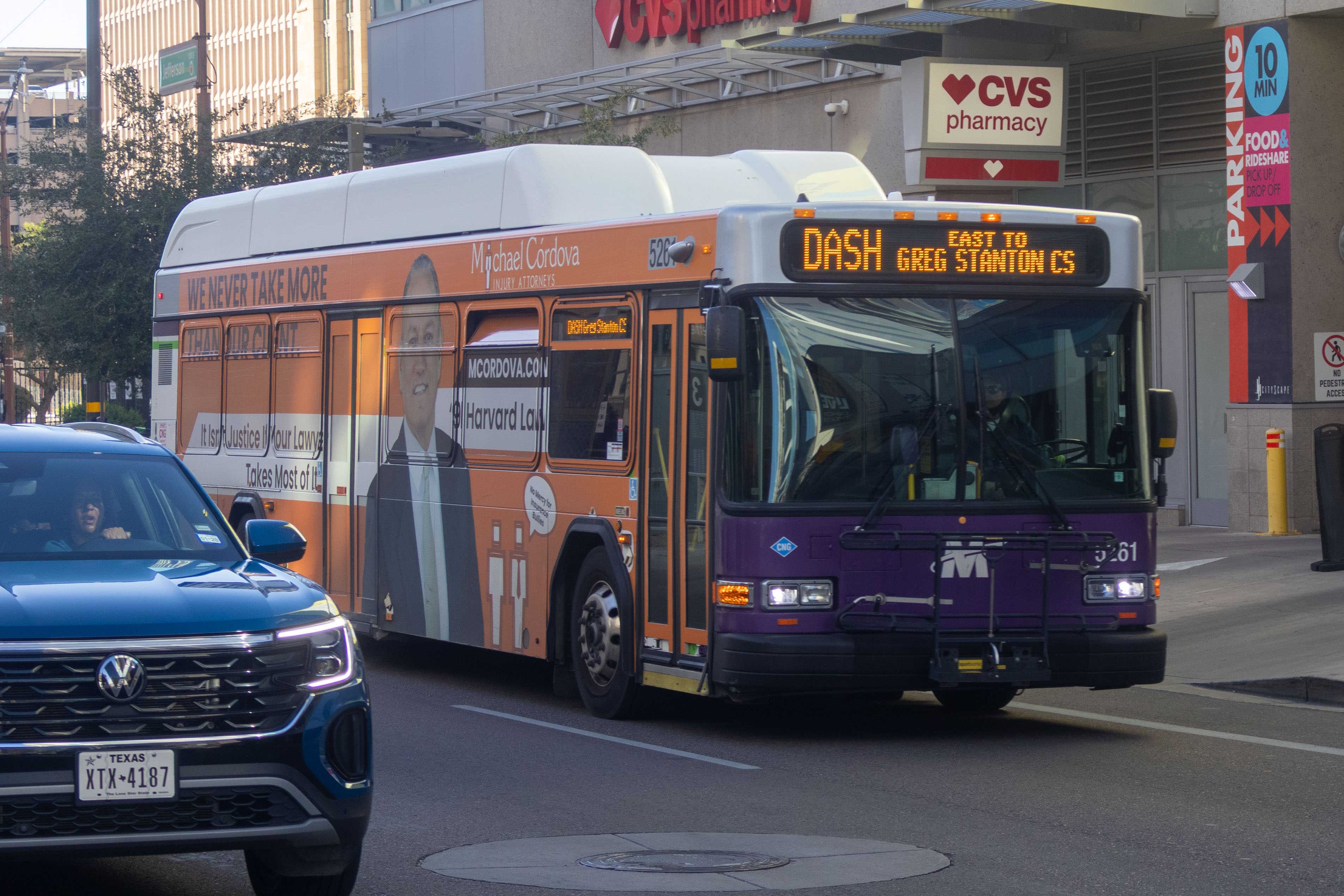 A white and gray Valley Metro bus, with purple and green accent colors, number 5261, traveling eastbound on Jefferson Street in Phoenix on the DASH route to Greg Stanton Central Station