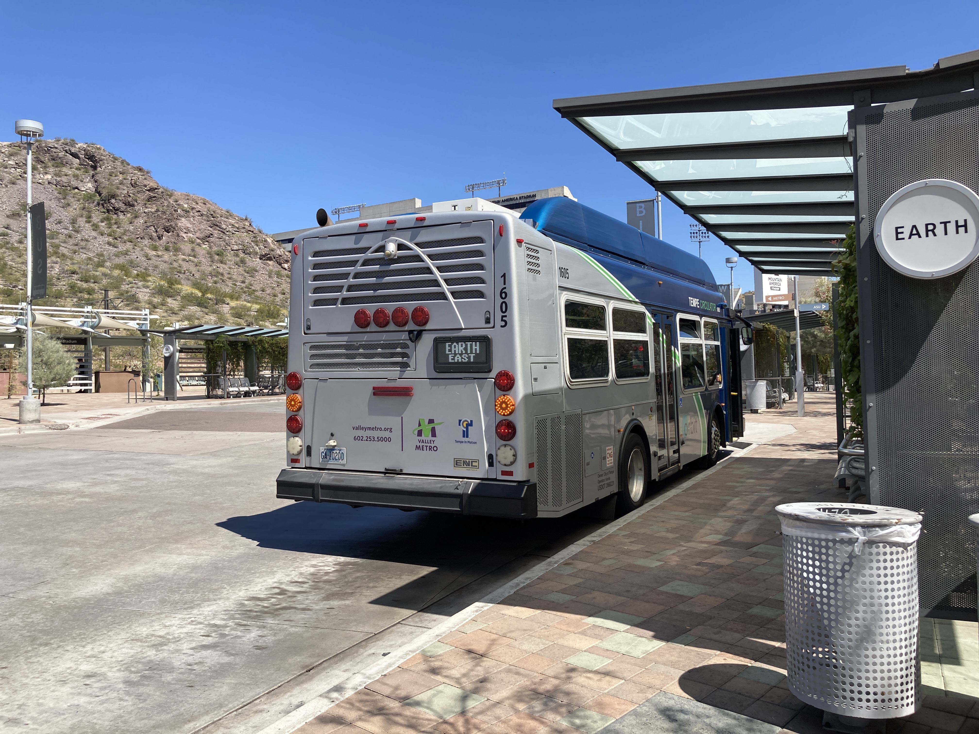 A gray and blue Orbit bus, with a green stripe, number 1605, at Tempe Transportation Center on the Earth route to Tempe Marketplace