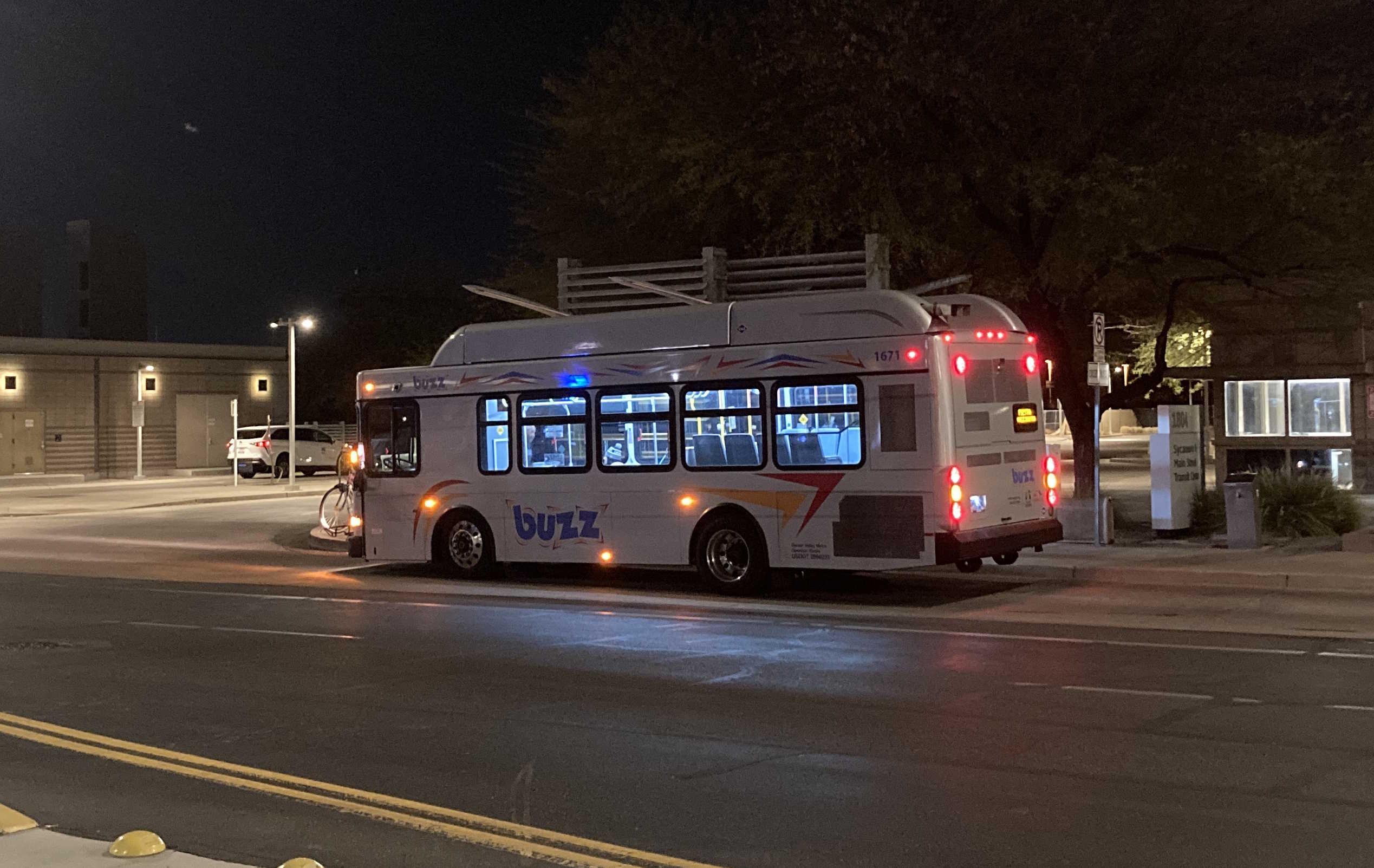 A silver BUZZ bus, with red, orange, and blue accents, number 1671, at Main Street and Sycamore in Mesa on the Fiesta BUZZ route to Alma School Road and Southern Avenue