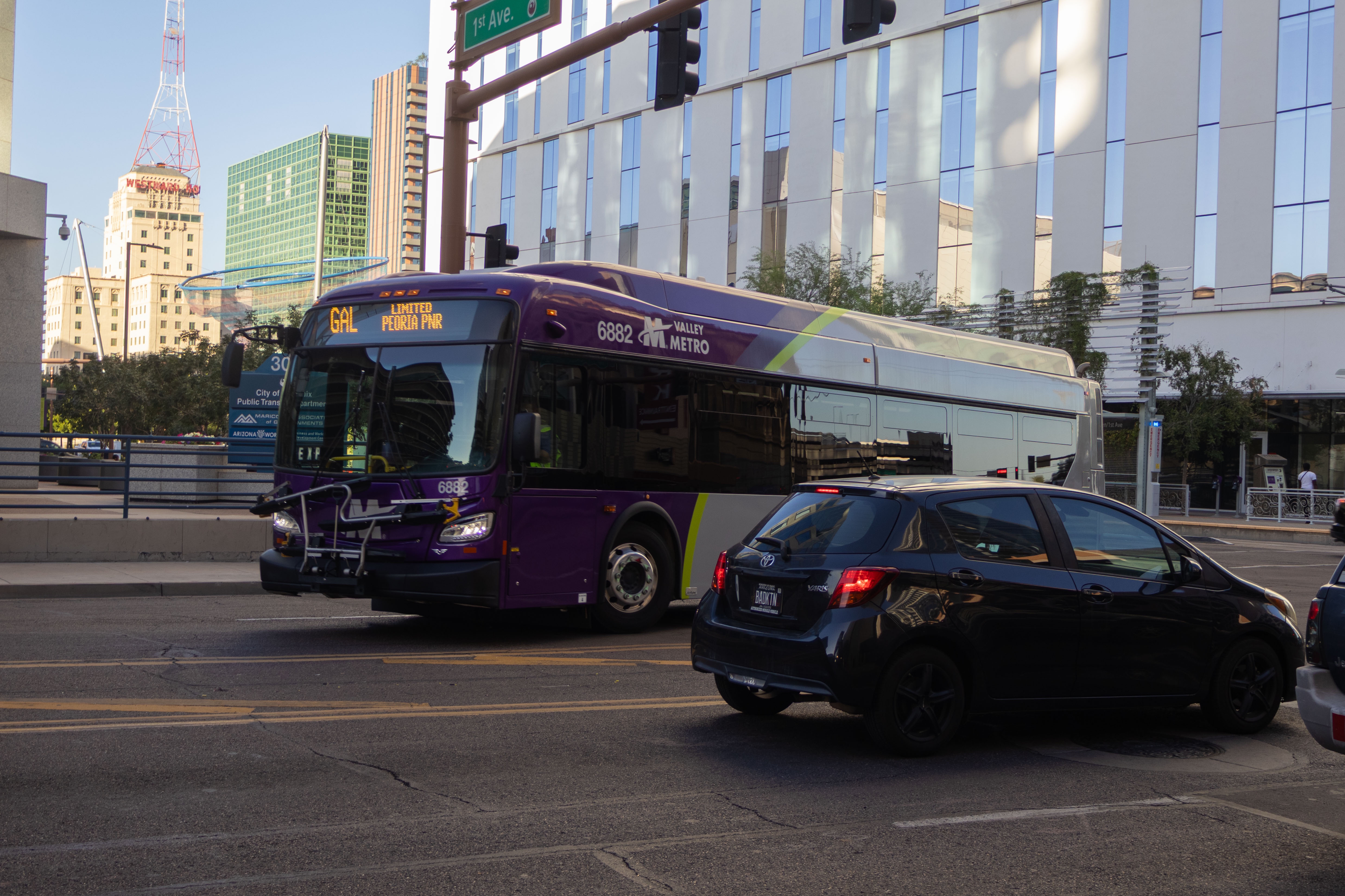 A gray and purple Valley Metro bus, with a green stripe, number 6882, traveling westbound on Van Buren Street in Phoenix on the Grand Avenue Limited route to Peoria Park and Ride