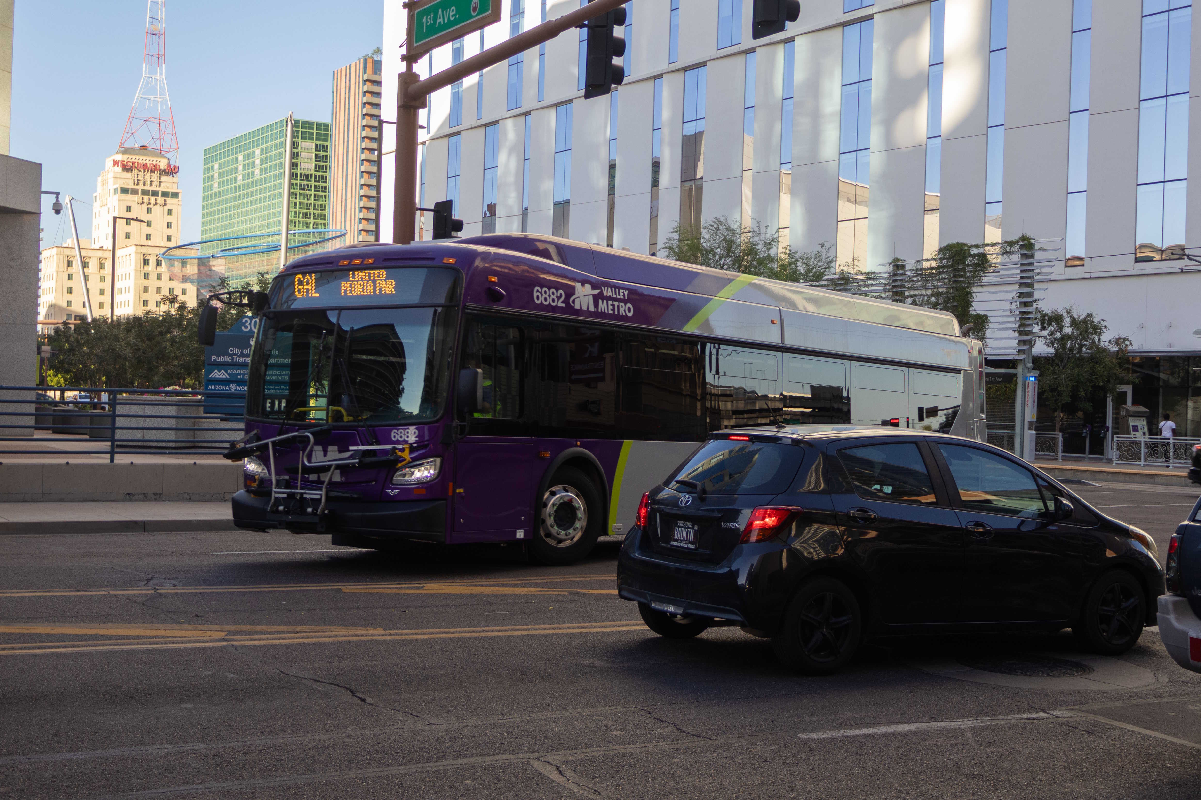 A gray and purple Valley Metro bus, with a green stripe, number 6882, traveling westbound on Van Buren Street in Phoenix on the Grand Avenue Limited route to Peoria Park and Ride