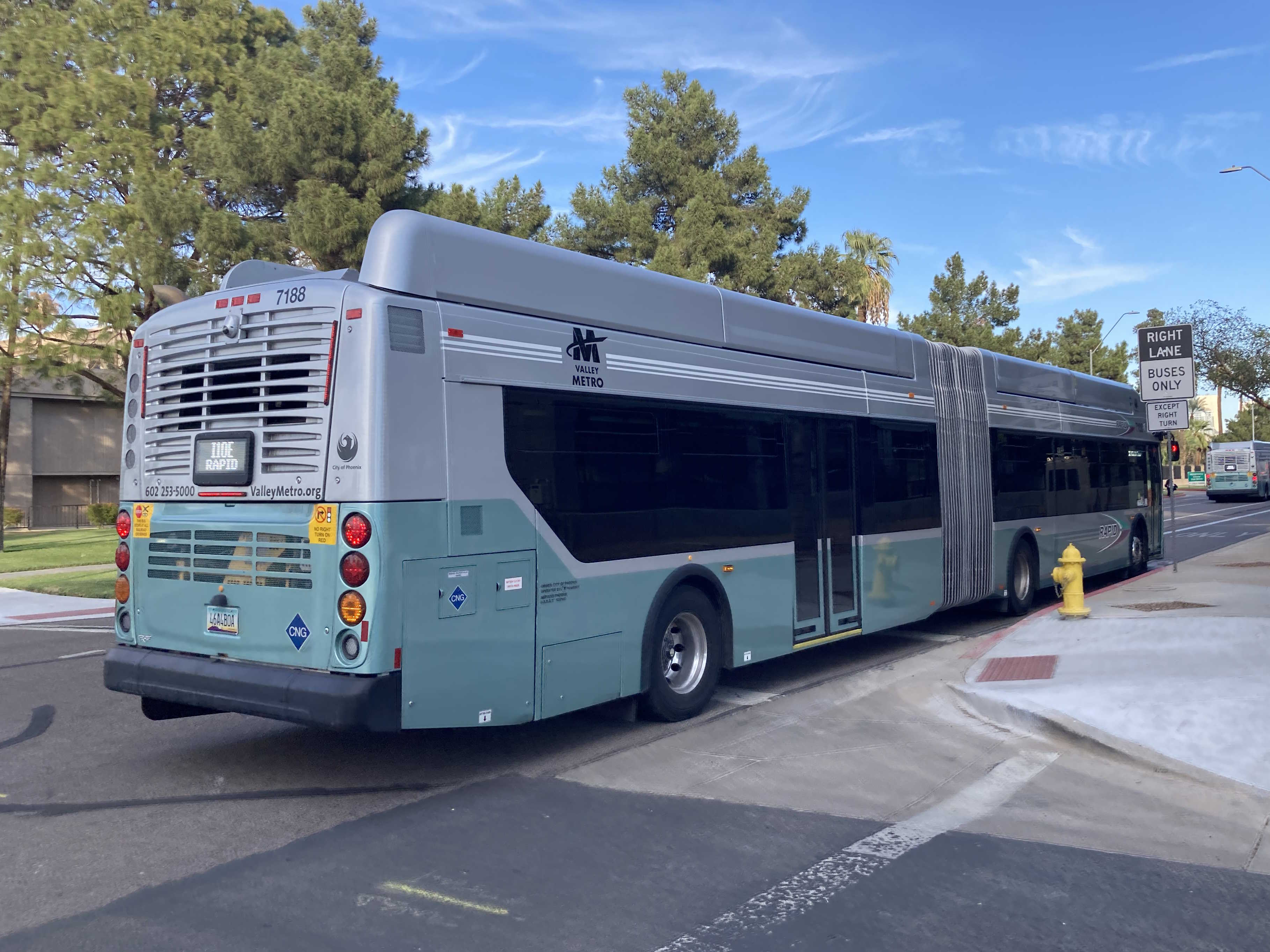 A silver and bluish-green Valley Metro RAPID bus, number 7188, traveling eastbound on Jefferson Street in Phoenix on the I-10 East RAPID route to 40th Street and Pecos Park and Ride