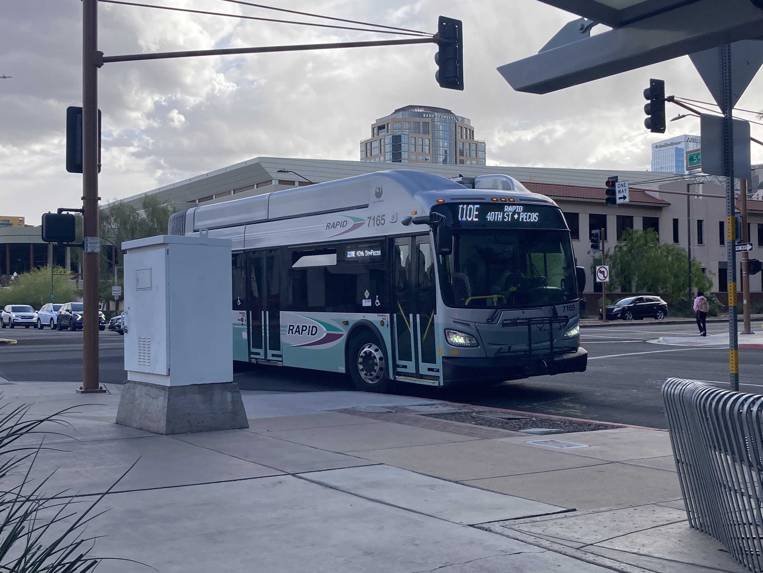 A silver and bluish-green Valley Metro RAPID bus, number 7165, traveling northbound on 5th Street in Phoenix on the I-10 East RAPID route to 40th Street and Pecos Park and Ride