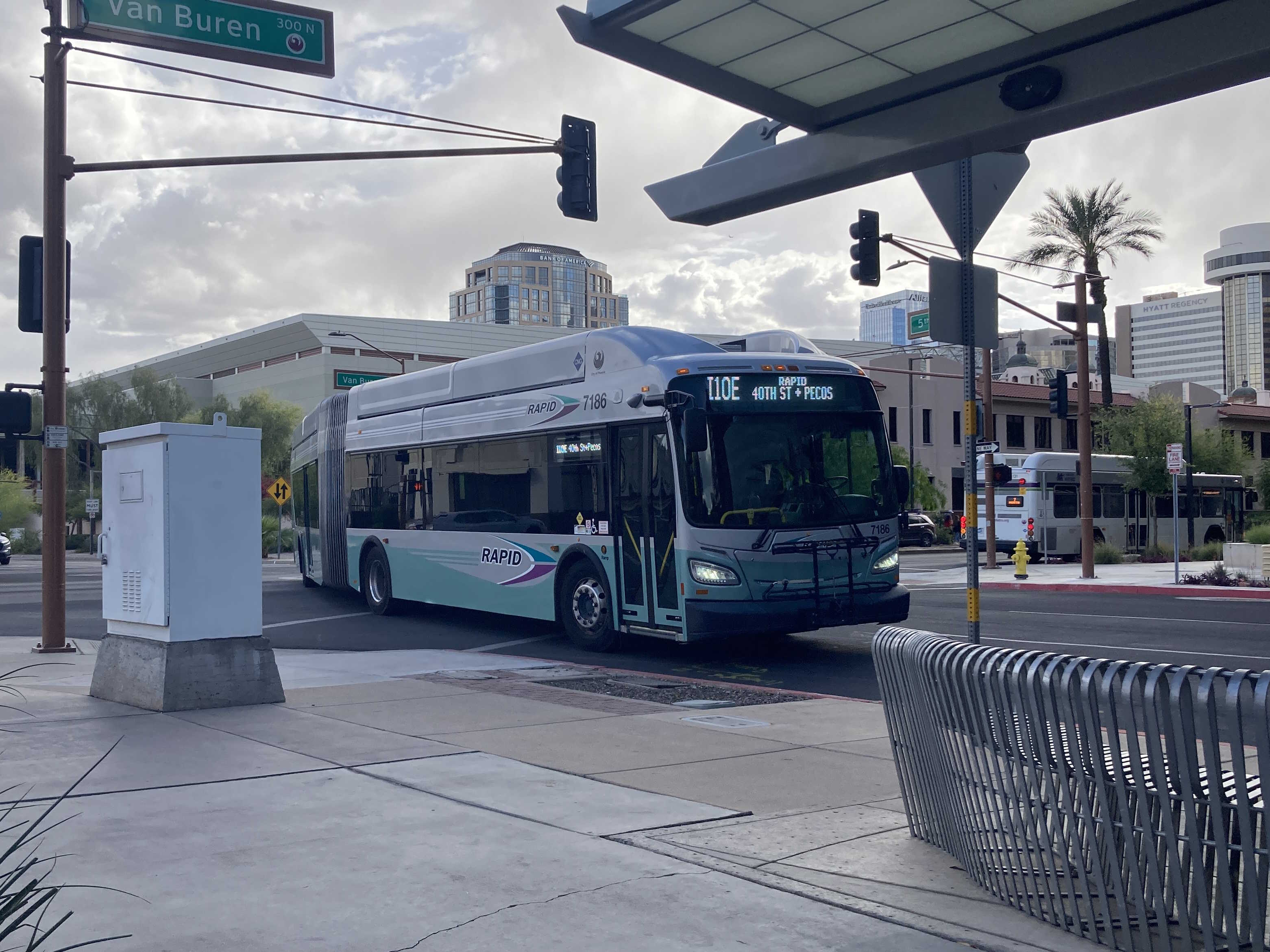 A silver and bluish-green Valley Metro RAPID bus, number 7186, traveling northbound on 5th Street in Phoenix on the I-10 East RAPID route to 40th Street and Pecos Park and Ride
