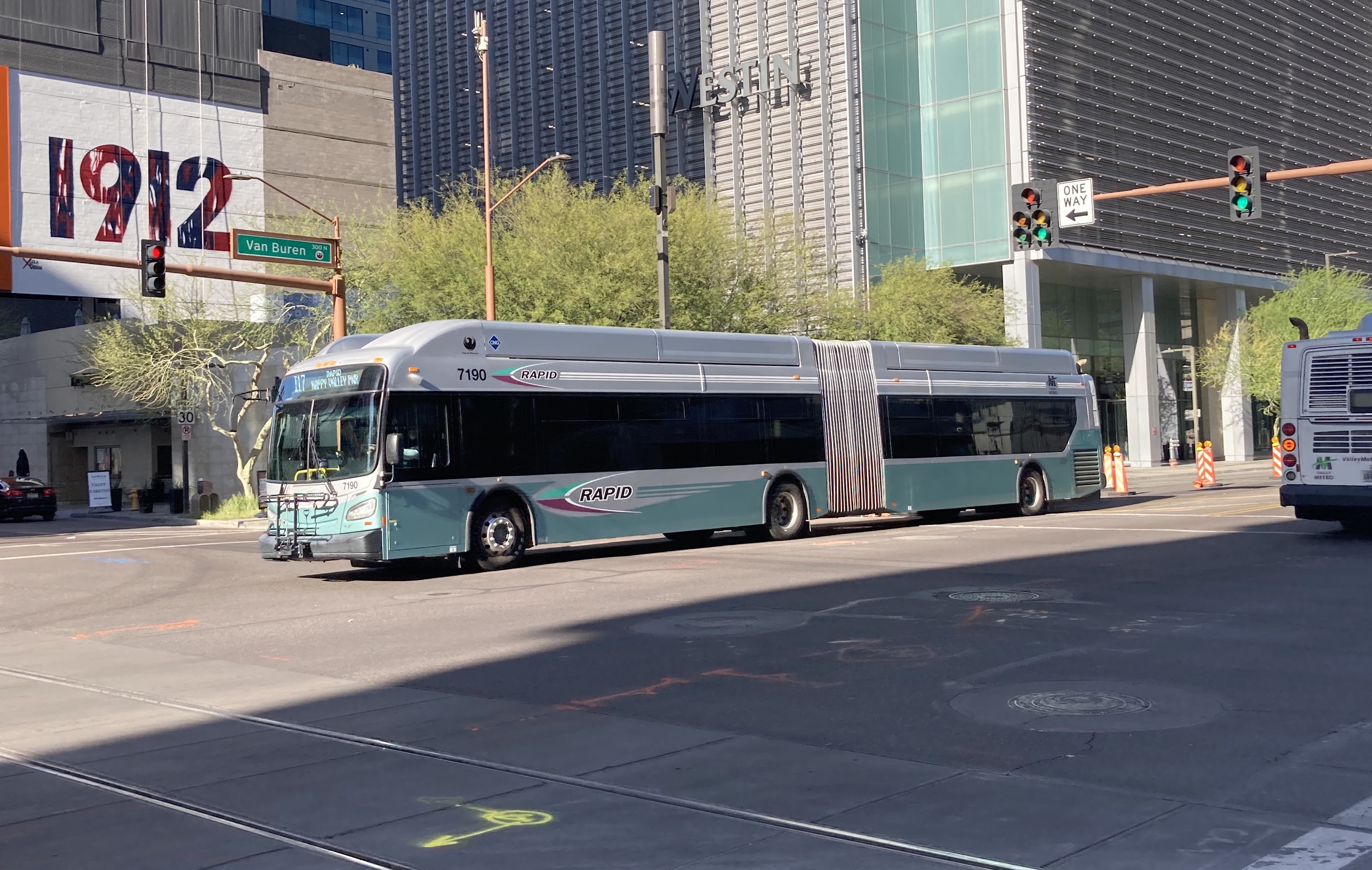 A silver and bluish-green articulated Valley Metro RAPID bus, number 7190, traveling westbound on Van Buren Street in Phoenix on the I-17 RAPID route to Happy Valley Park and Ride