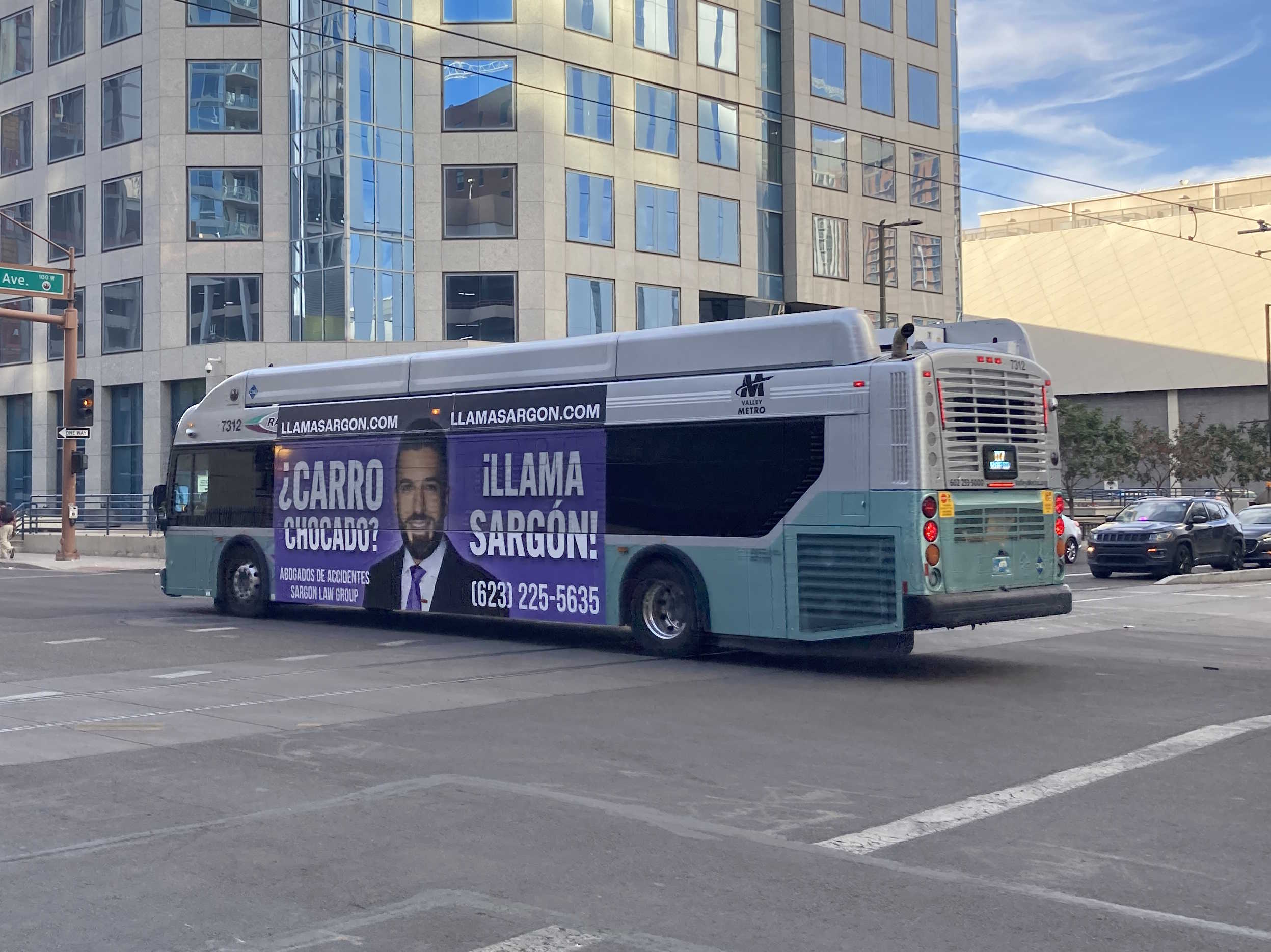 A silver and bluish-green Valley Metro RAPID bus, number 7312, traveling westbound on Van Buren Street in Phoenix on the I-17 RAPID route to Thelda Williams Transit Center