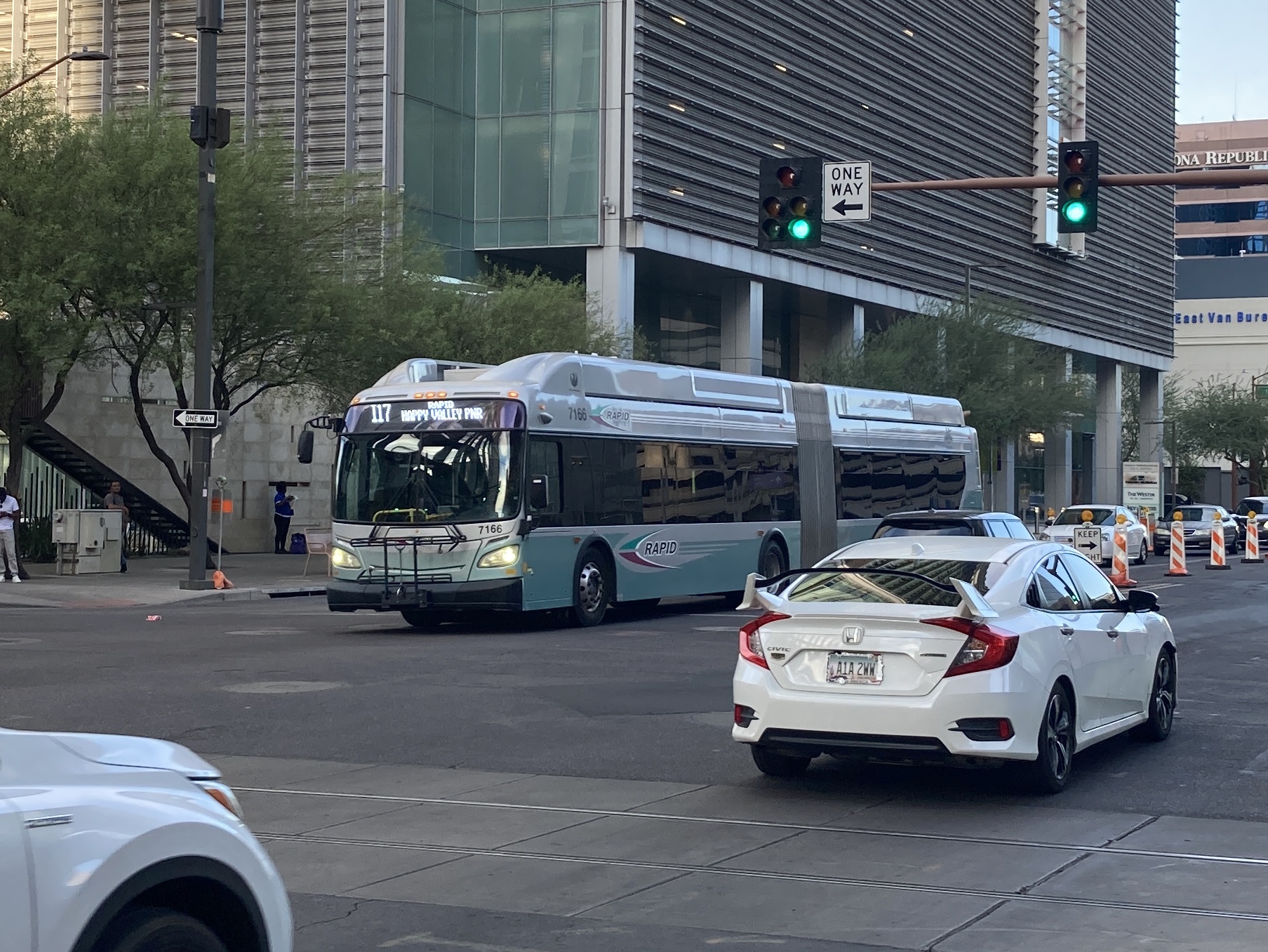 A silver and bluish-green articulated Valley Metro RAPID bus, number 7166, traveling westbound on Van Buren Street in Phoenix on the I-17 RAPID route to Happy Valley Park and Ride