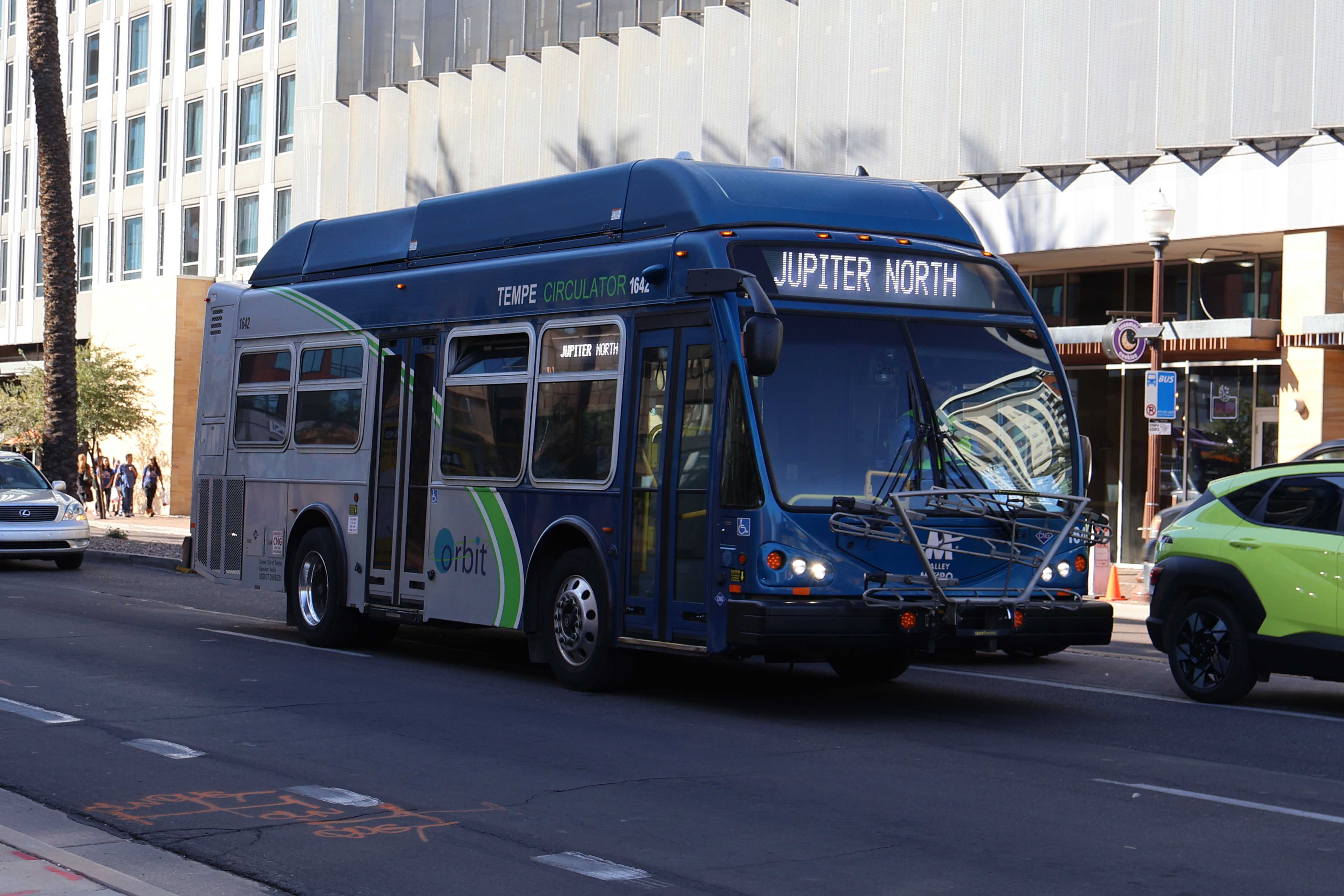 A gray and blue Orbit bus, with a green stripe, number 1642, traveling eastbound on University Drive on the Jupiter route to Tempe Transportation Center