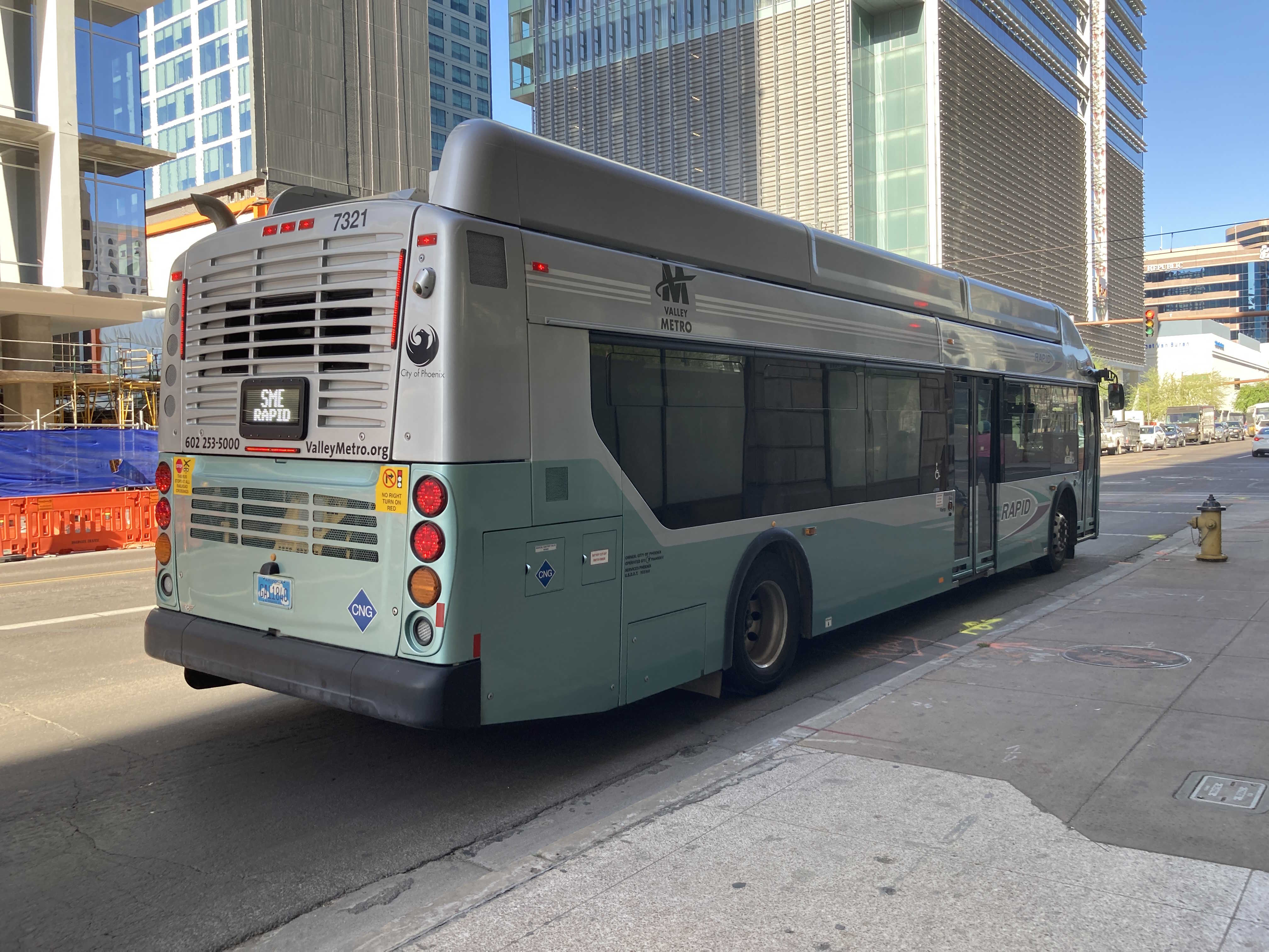 A silver and bluish-green Valley Metro RAPID bus, number 7321, traveling eastbound on Van Buren Street in Phoenix on the South Mountain East RAPID route to 24th Street and Baseline Park and Ride