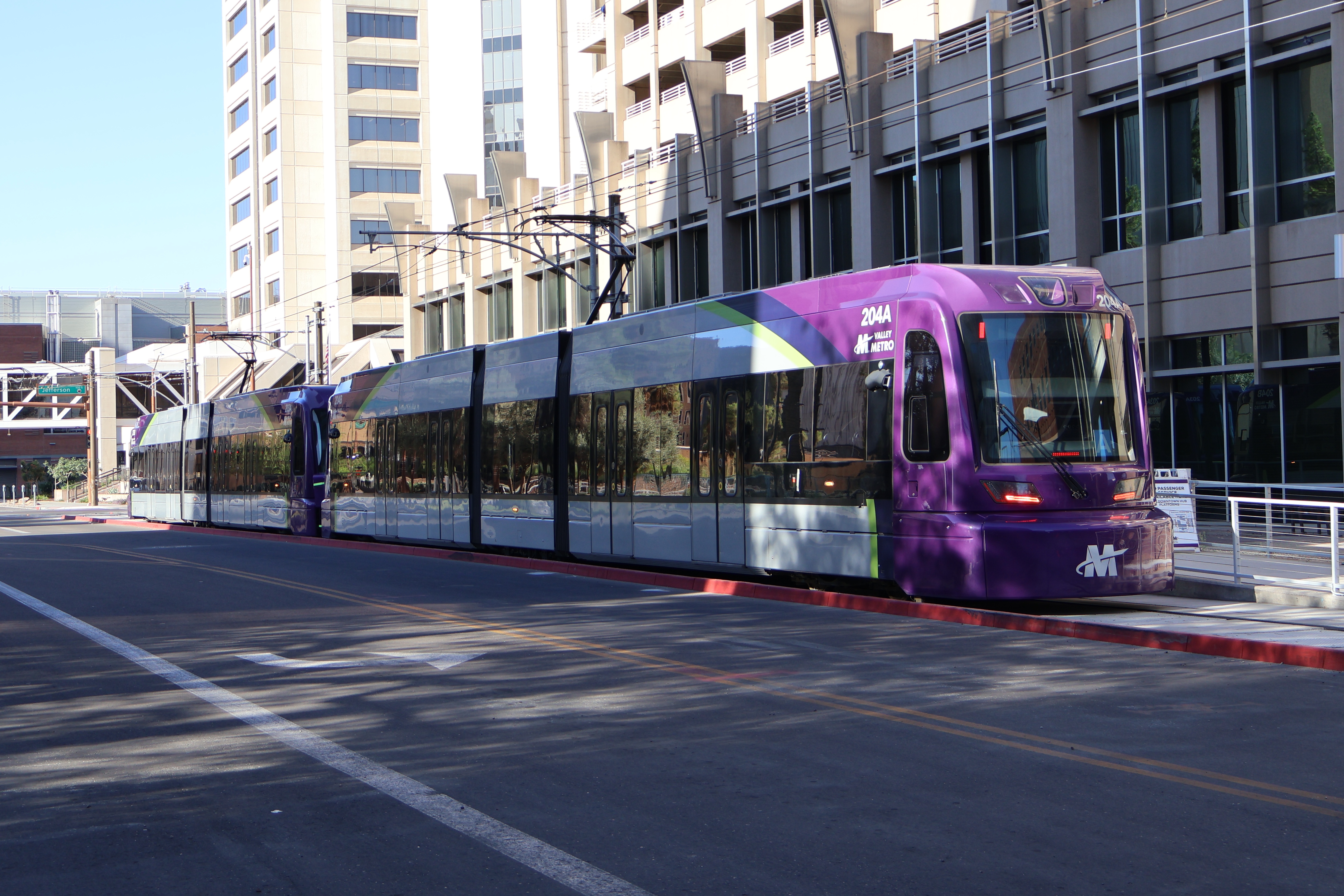 Two gray and purple light rail trains with green stripes, numbers 204 and 203, parked at 3rd Avenue and Washington Street station in Phoenix
