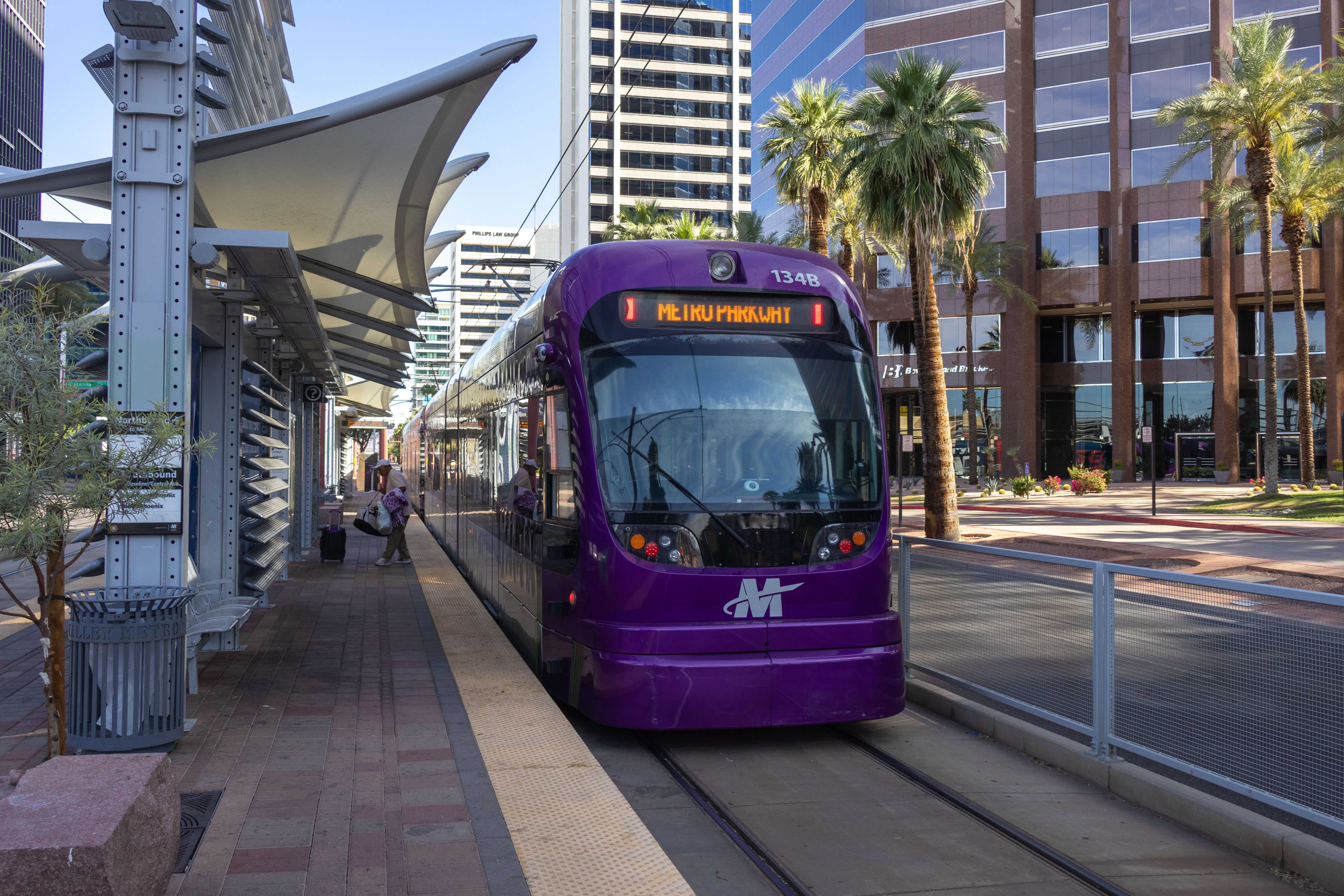 A gray and purple light rail train with a green stripe, number 134, traveling northbound on Central Avenue in Phoenix