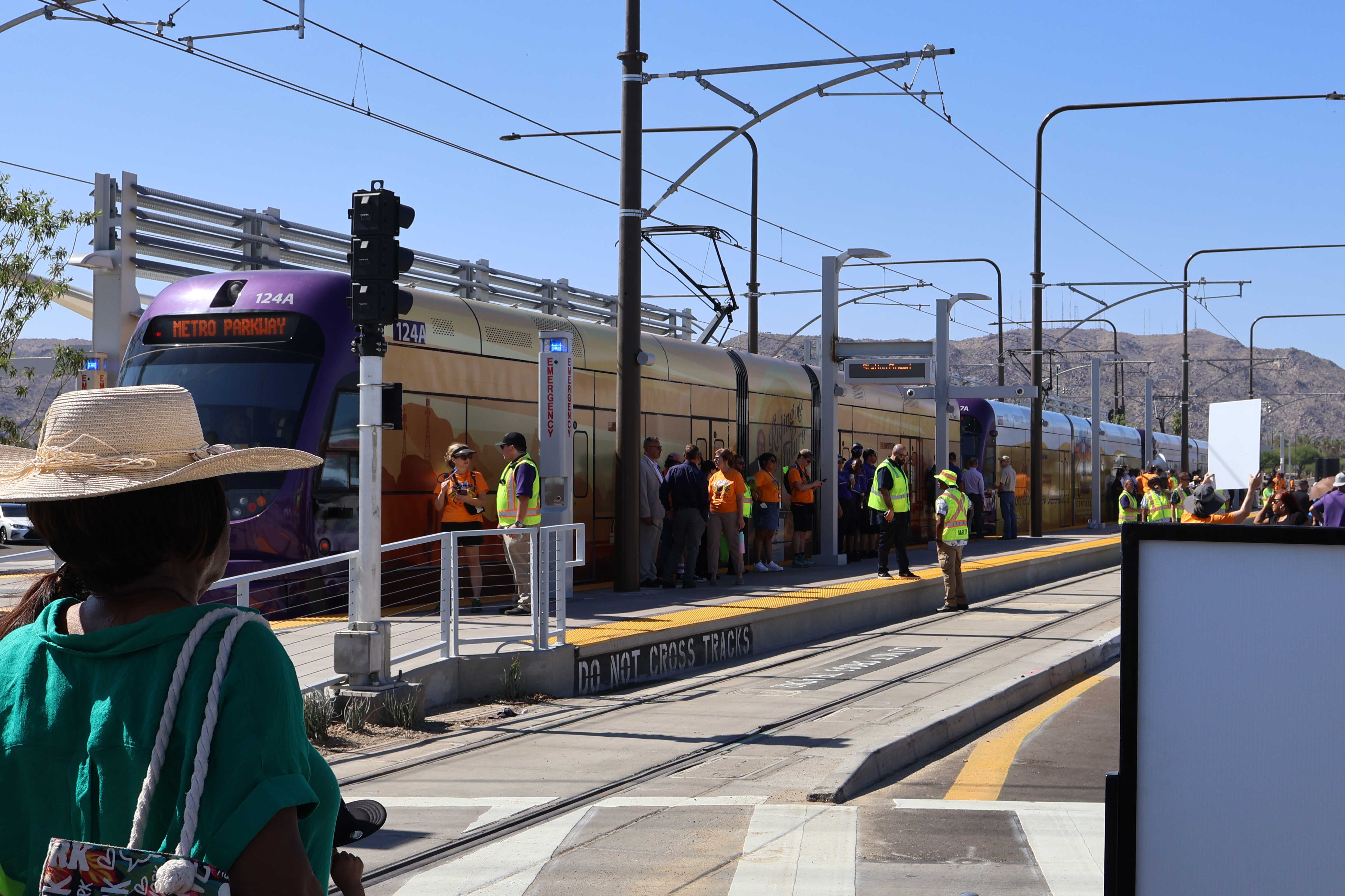 Three gray and purple light rail trains with green stripes, numbers 124, 147, and 104, traveling northbound on Central Avenue in Phoenix