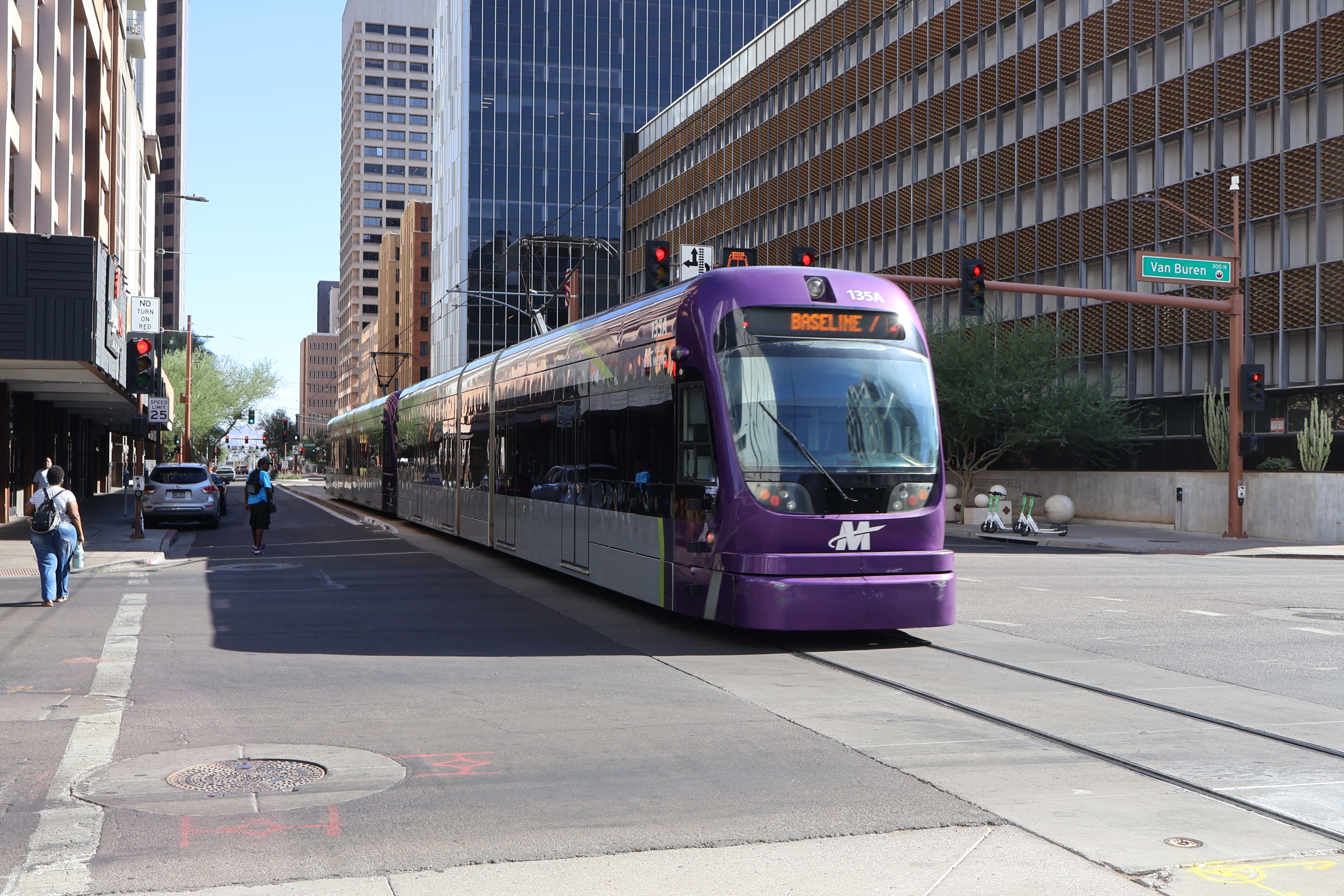 Two gray and purple light rail trains with green stripes, numbers 114 and 135, traveling southbound on 1st Avenue in Phoenix