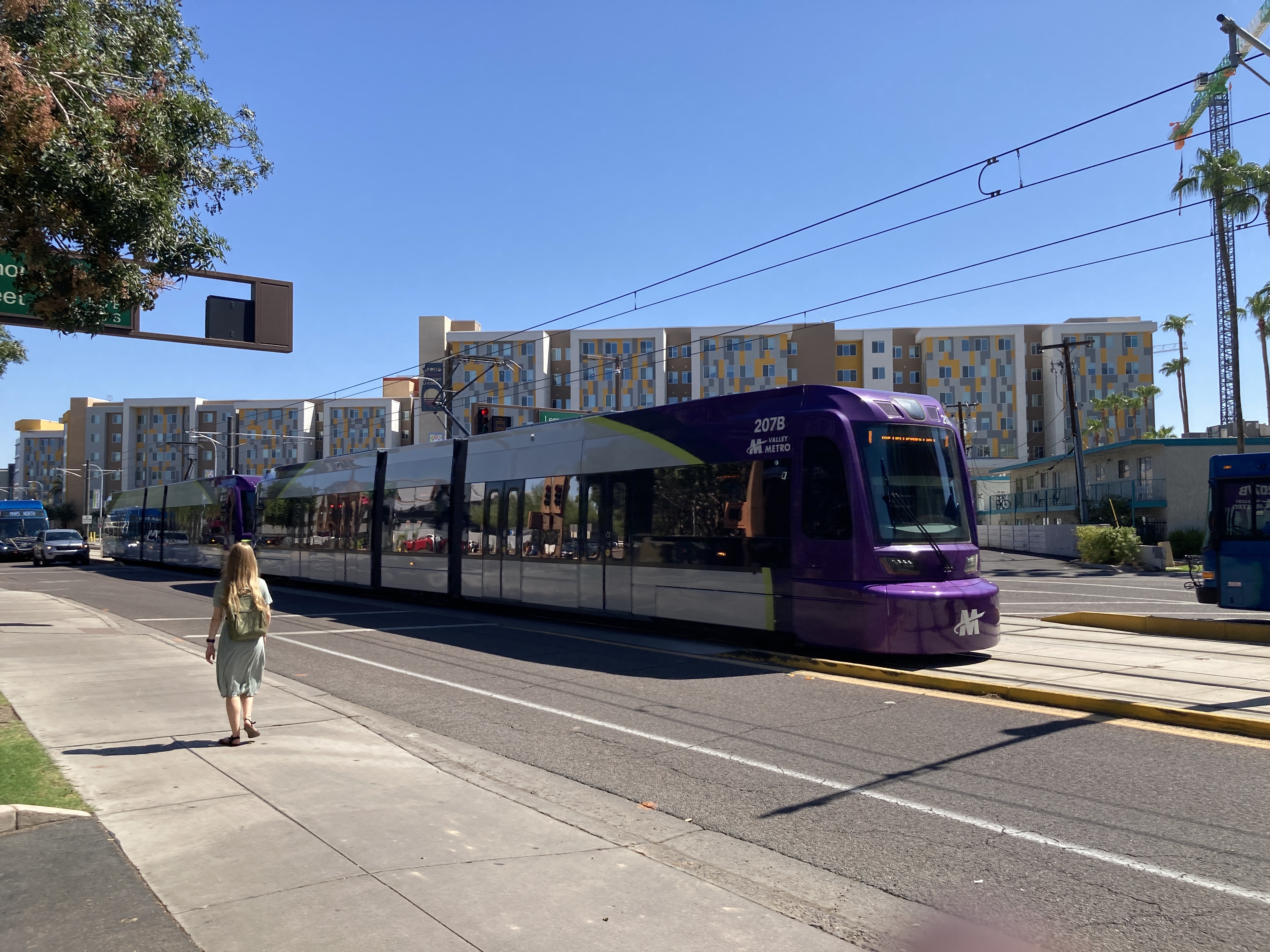 Two gray and purple light rail trains with green stripes, numbers 206 and 207, traveling westbound on Terrace Road towards Metro Parkway station