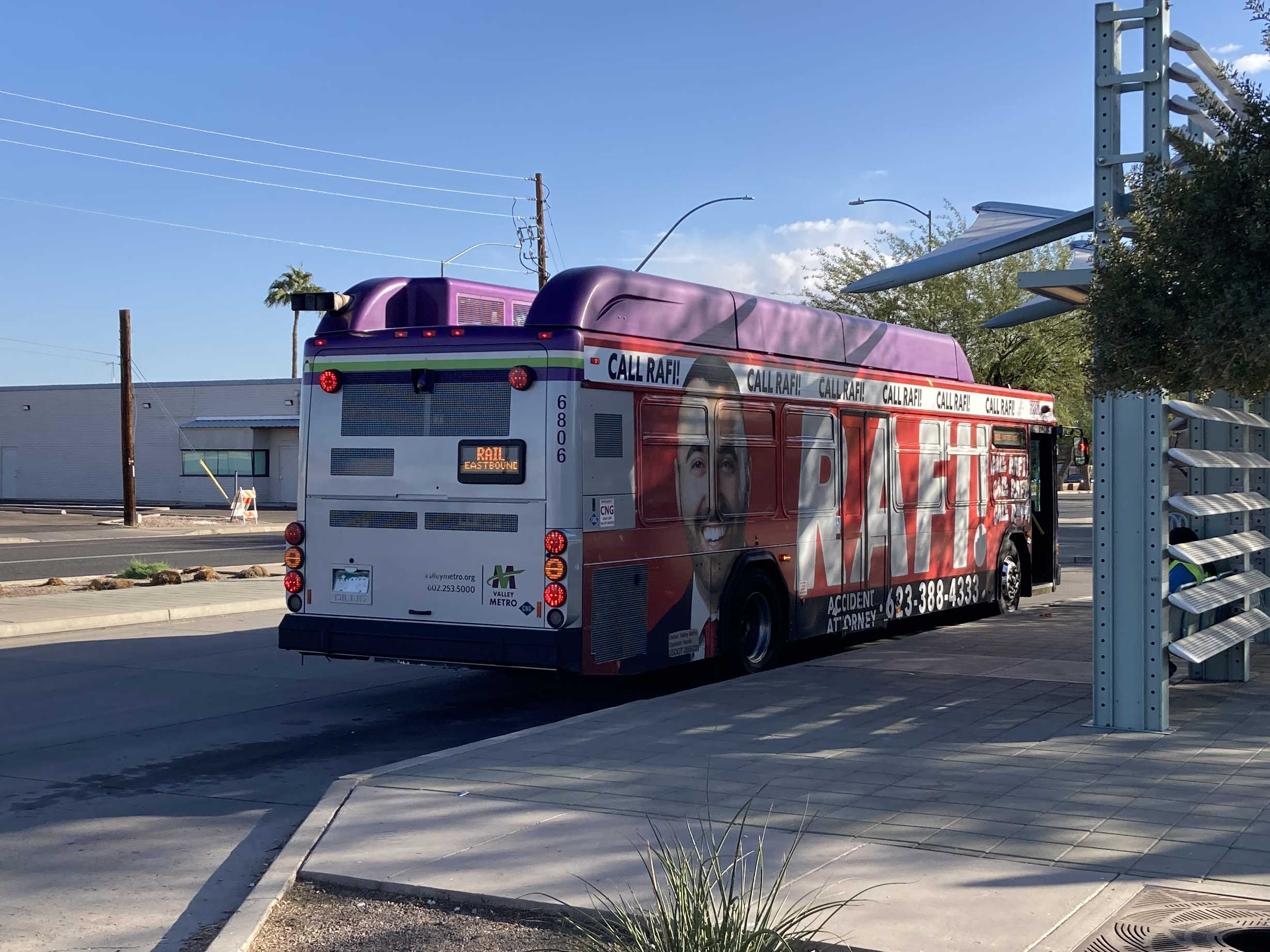 A gray and purple Valley Metro bus with a white and green stripe, number 6806, at Sycamore / Main Street Transit Center as an eastbound light rail shuttle