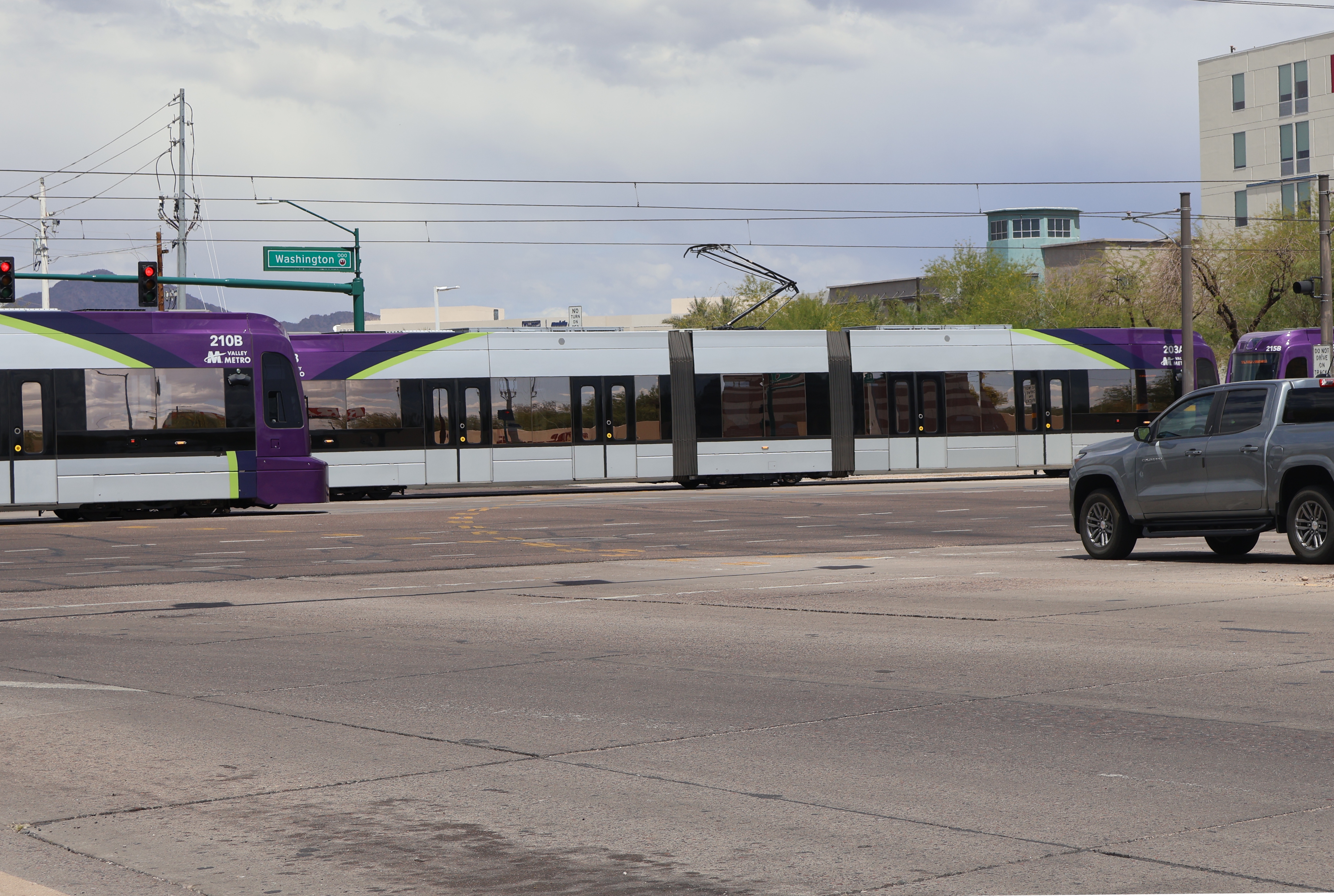 Two gray and purple light rail trains with green stripes, numbers 210, 203, and 205, at 44th Street in Phoenix