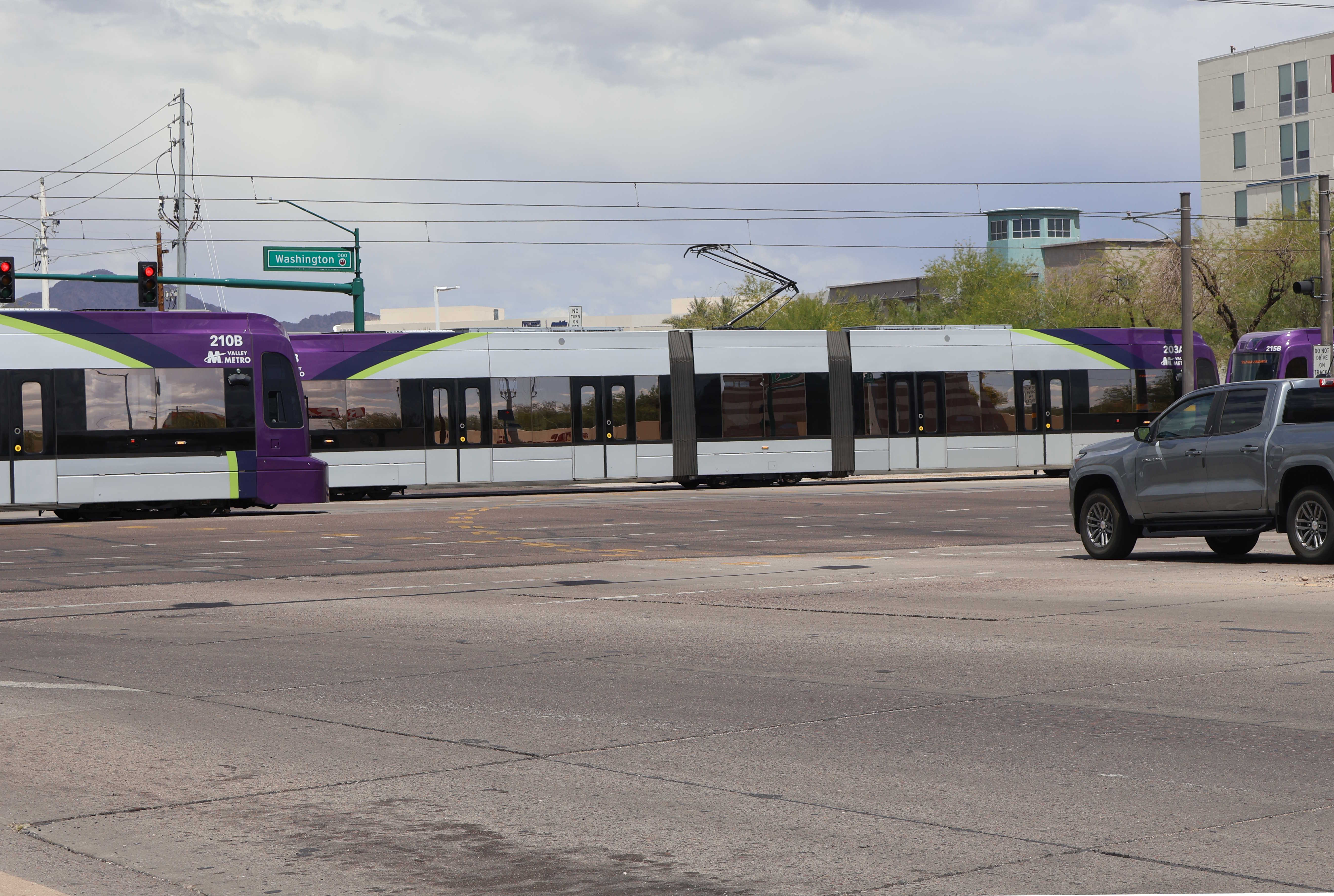 Two gray and purple light rail trains with green stripes, numbers 210, 203, and 205, at 44th Street in Phoenix