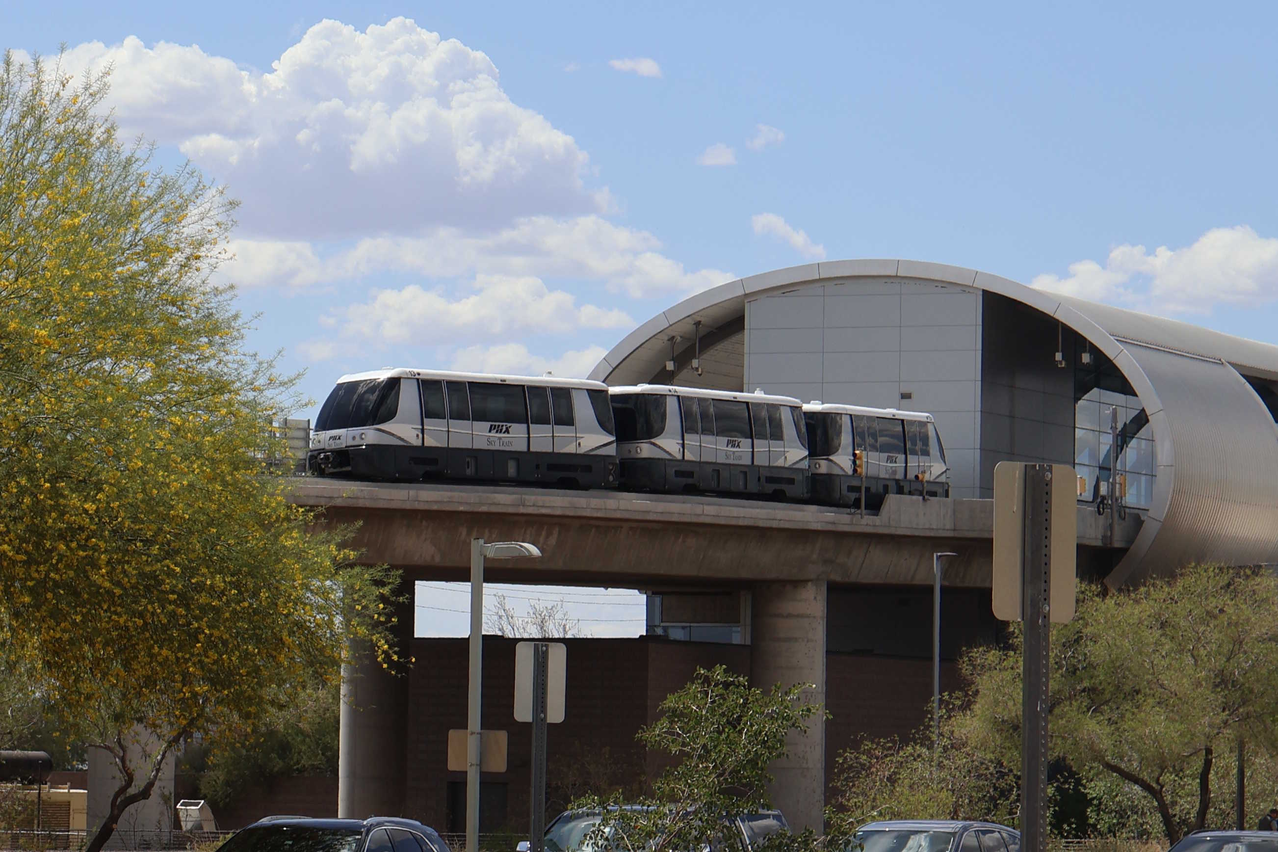 A gray automated rail vehicle, with black and white stripes, numbers 13, 14, and 15, entering 44th Street Station on the PHX Sky Train route to 44th Street Station